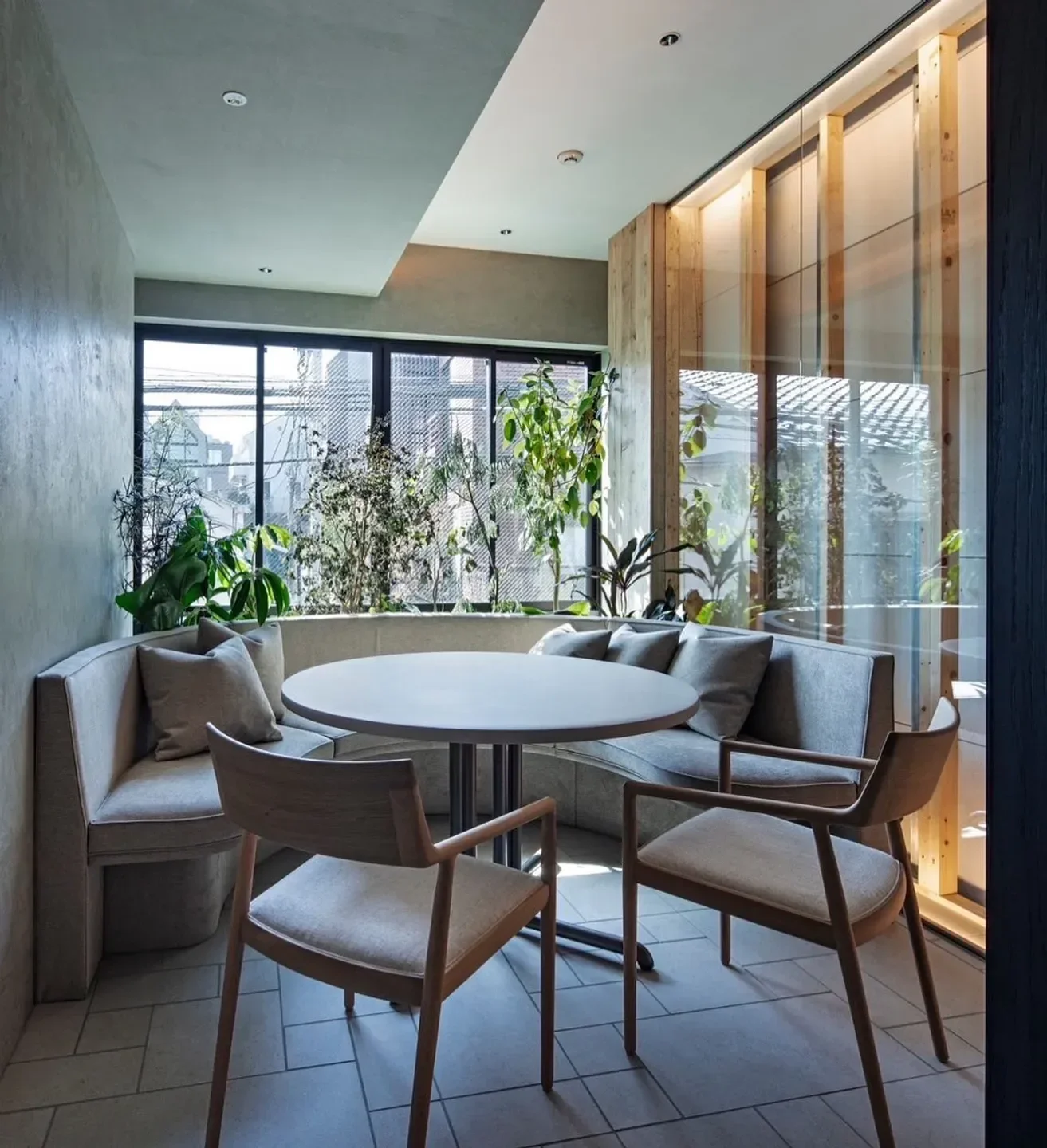 Cozy dining area at L'ÉTERRE restaurant in Tokyo, featuring a table, chairs, and greenery.