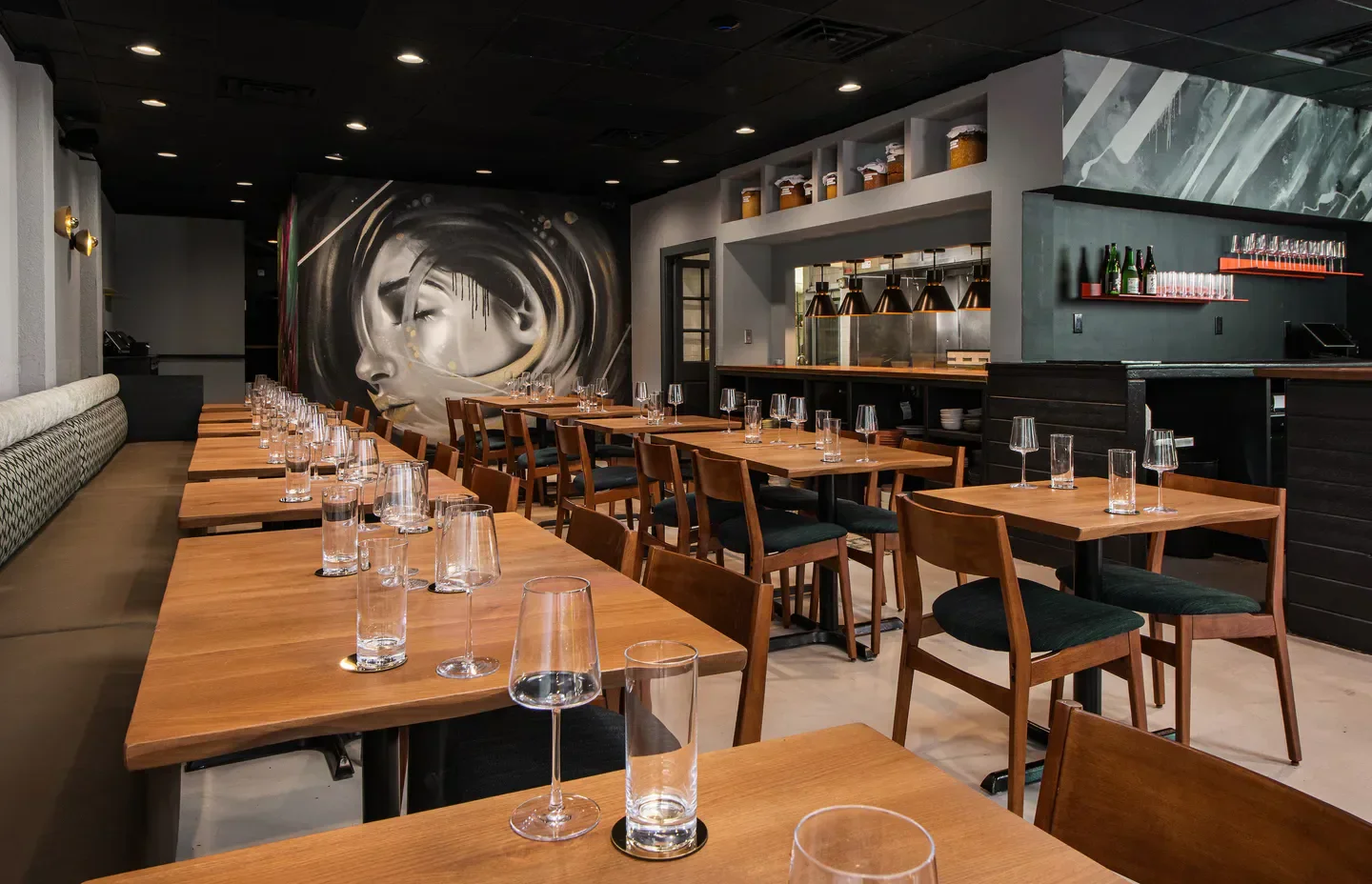 Interior dining space at Lion & the Rambler in Miami, with art and wooden tables.