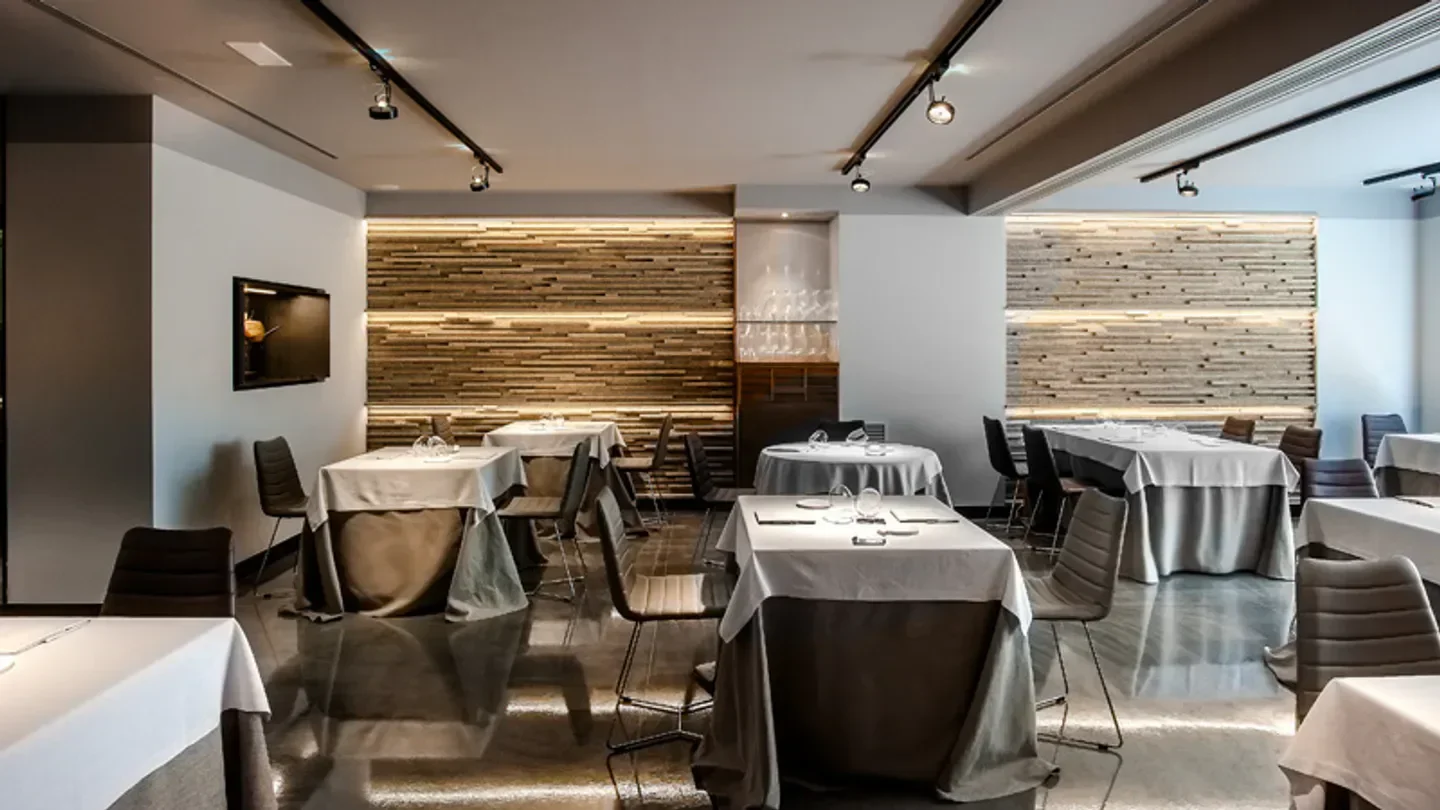 Interior of Lluerna restaurant in Barcelona, showcasing elegant dining tables and decor.