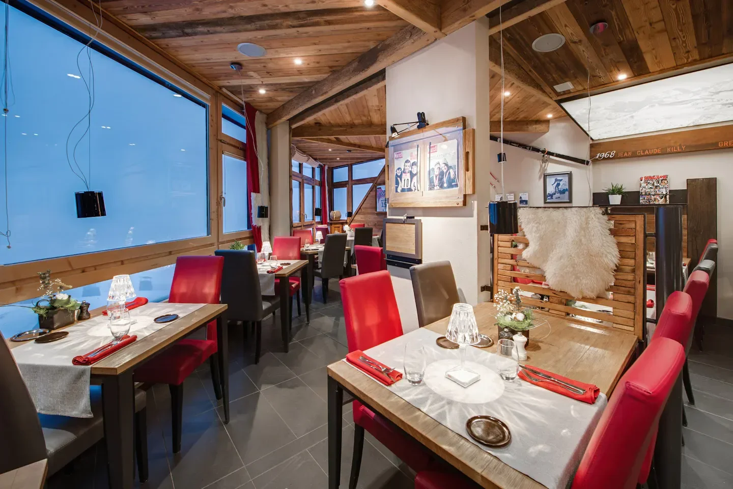 Cozy interior of L'Olympiski restaurant in Val Thorens, with wooden decor and tables.