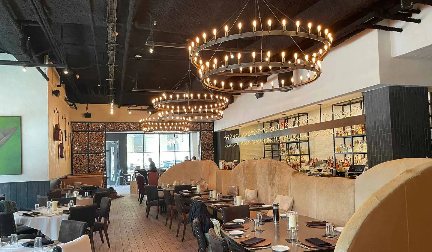 Elegant dining area at Lonesome Dove Bistro - Austin, with chandeliers and bar in Austin.