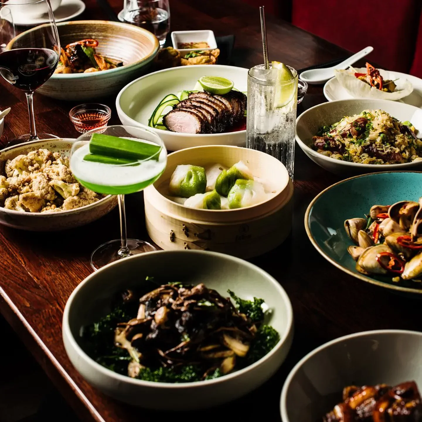 Delicious dishes at Lotus Double Bay in Sydney, including dumplings and cocktails, on a dark wooden table