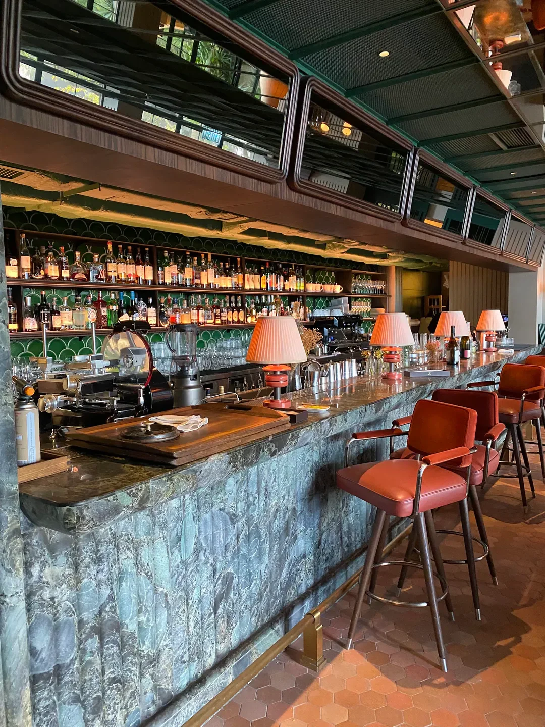 Stylish bar at Louise restaurant in Hong Kong, featuring lamps, bar stools, and bottles.