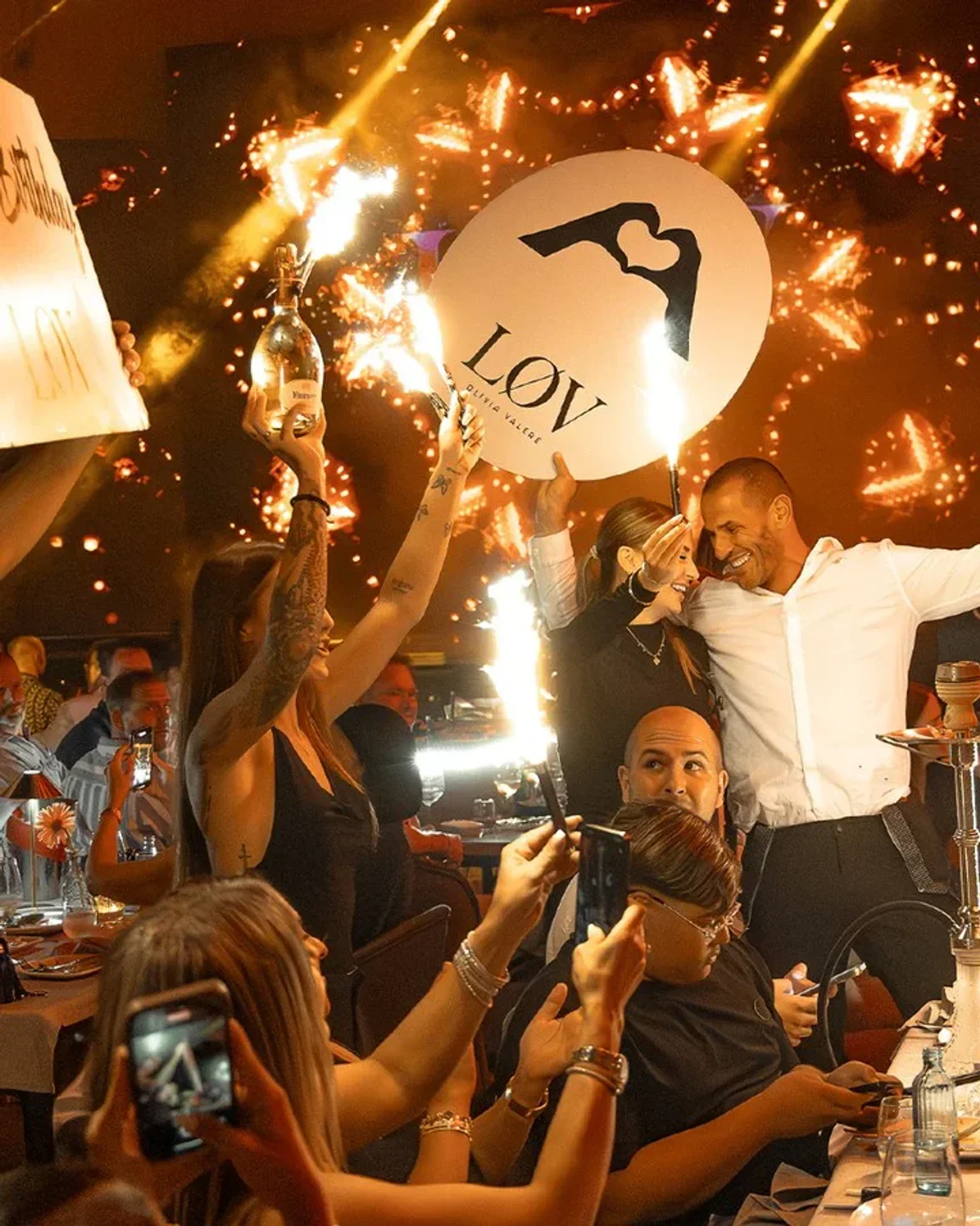 Celebration with sparklers and champagne at LOV Olivia Valere nightclub in Marbella, guests capturing the moment.