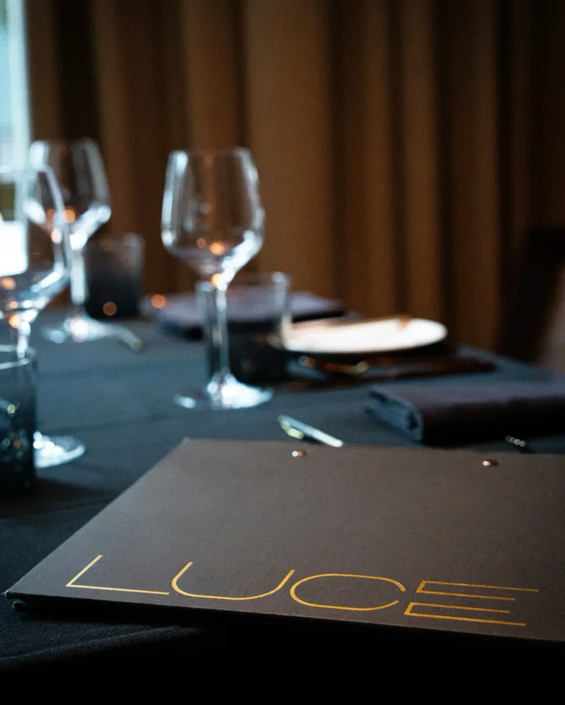 Table setting at LUCE restaurant in San Francisco, with wine glasses and menu