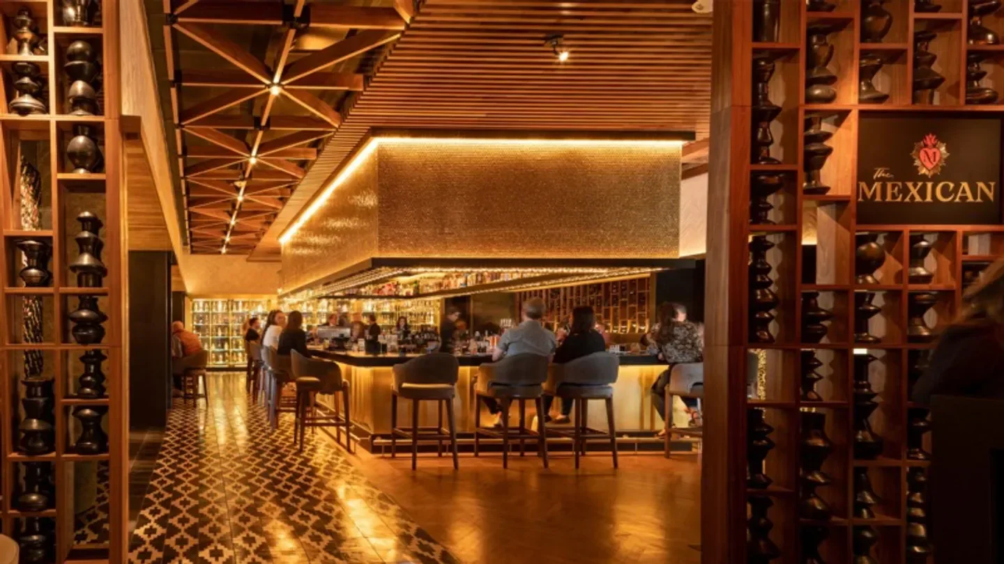 Lucia restaurant in Dallas, featuring a stylish bar with wooden decor and guests.