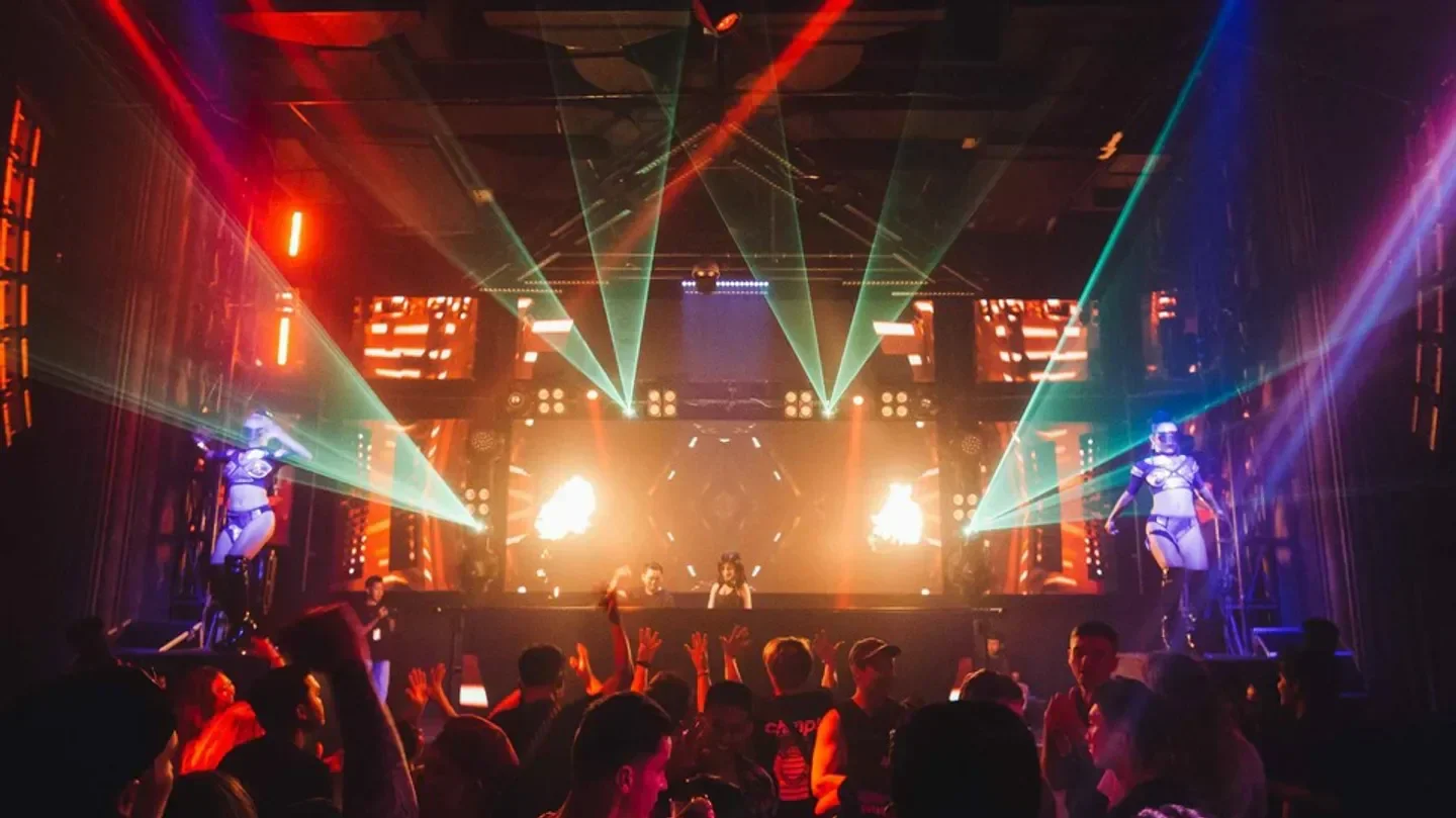 Energetic nightclub scene at LXXY Bali, with lights, dancers, and a lively crowd.