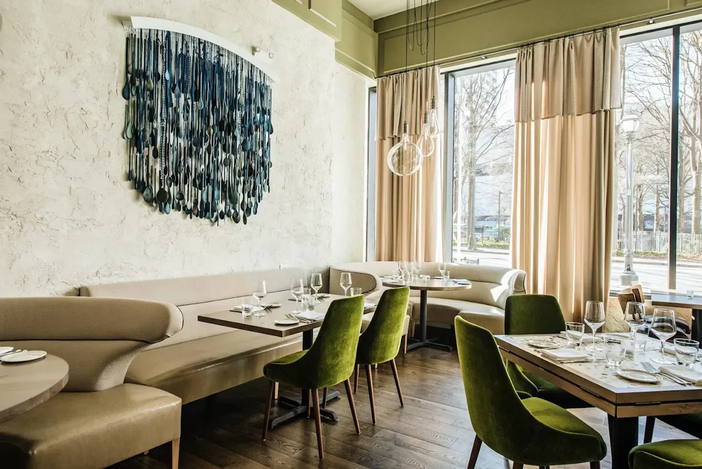 Interior of Lyla Lila restaurant in Atlanta featuring a unique wall art and green chairs.