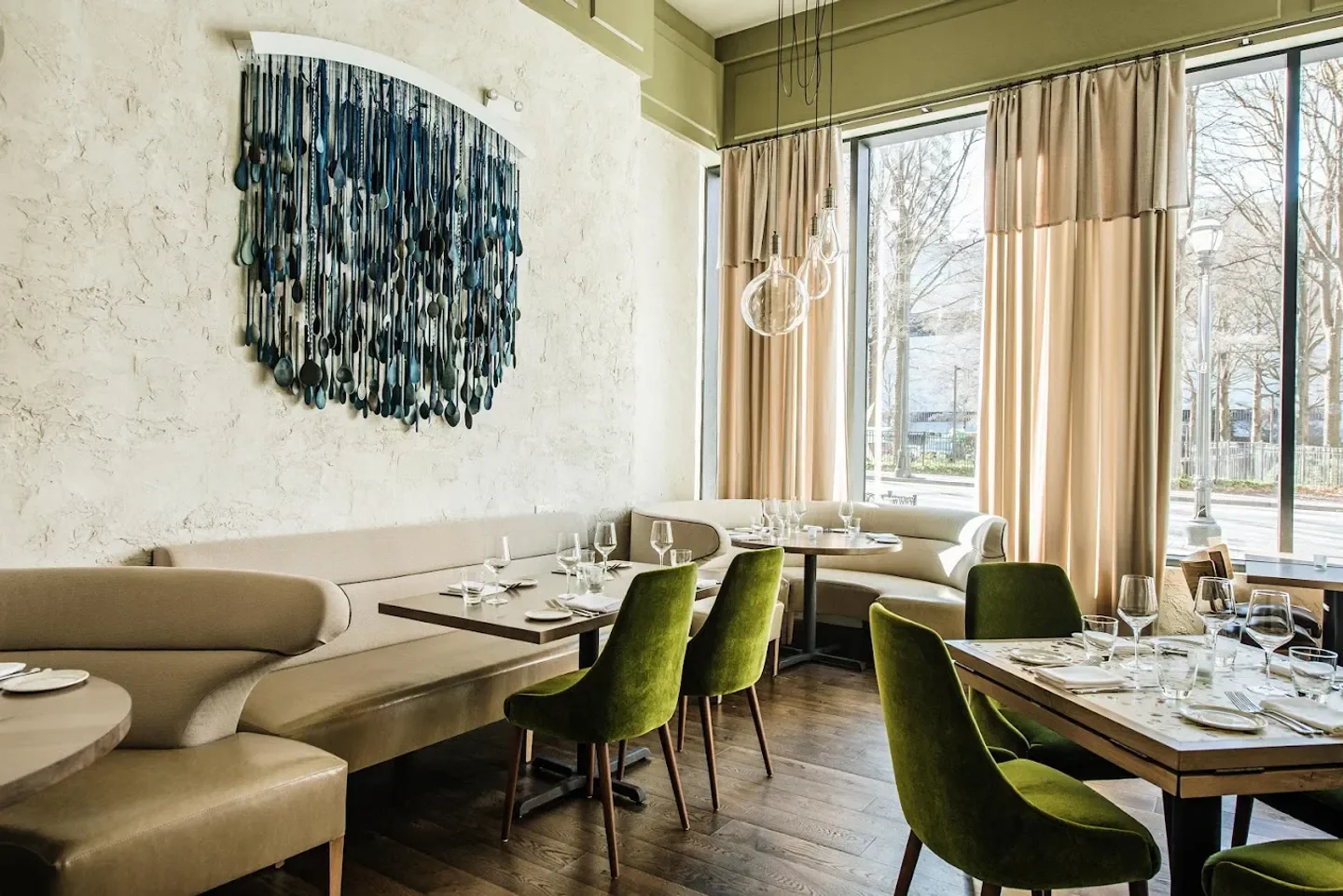 Interior of Lyla Lila restaurant in Atlanta featuring a unique wall art and green chairs.
