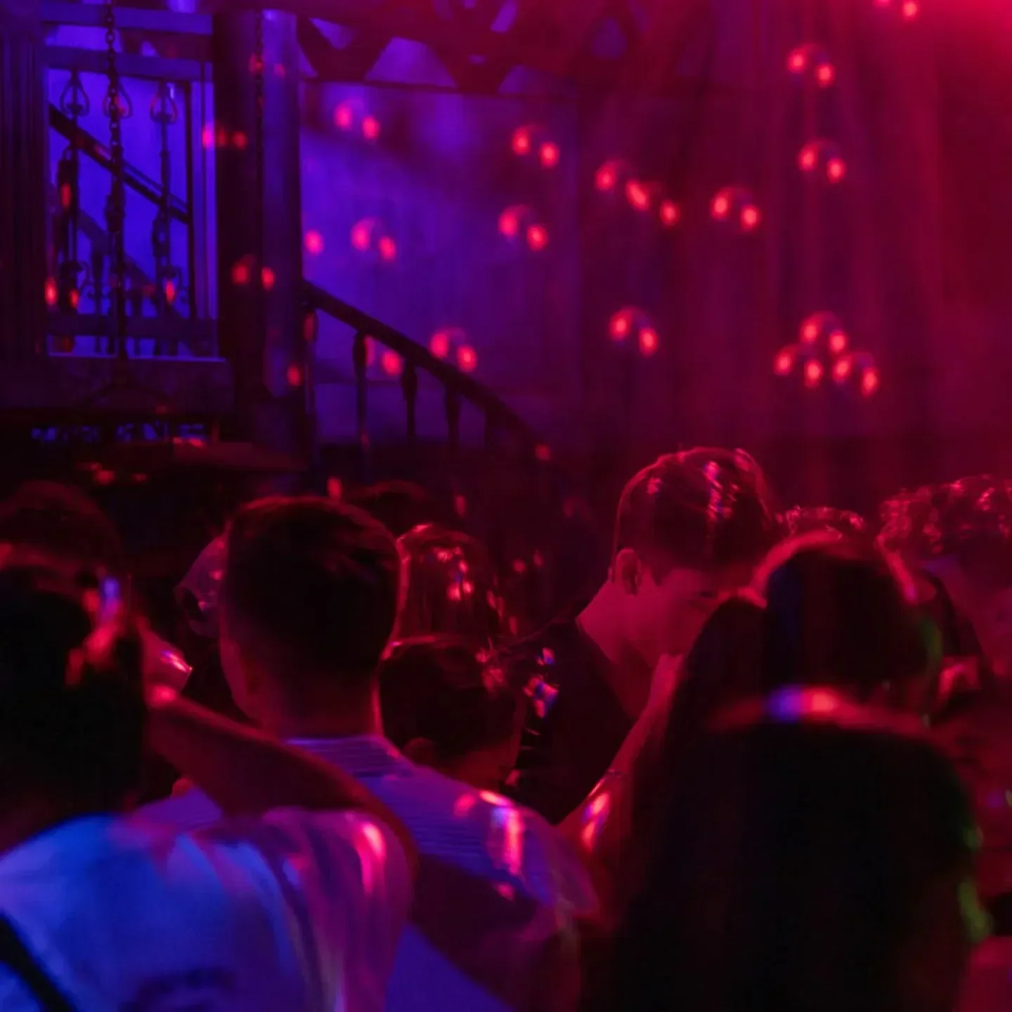 Inside Maggie Choo's nightclub in Hong Kong, people dancing under red and purple lights.