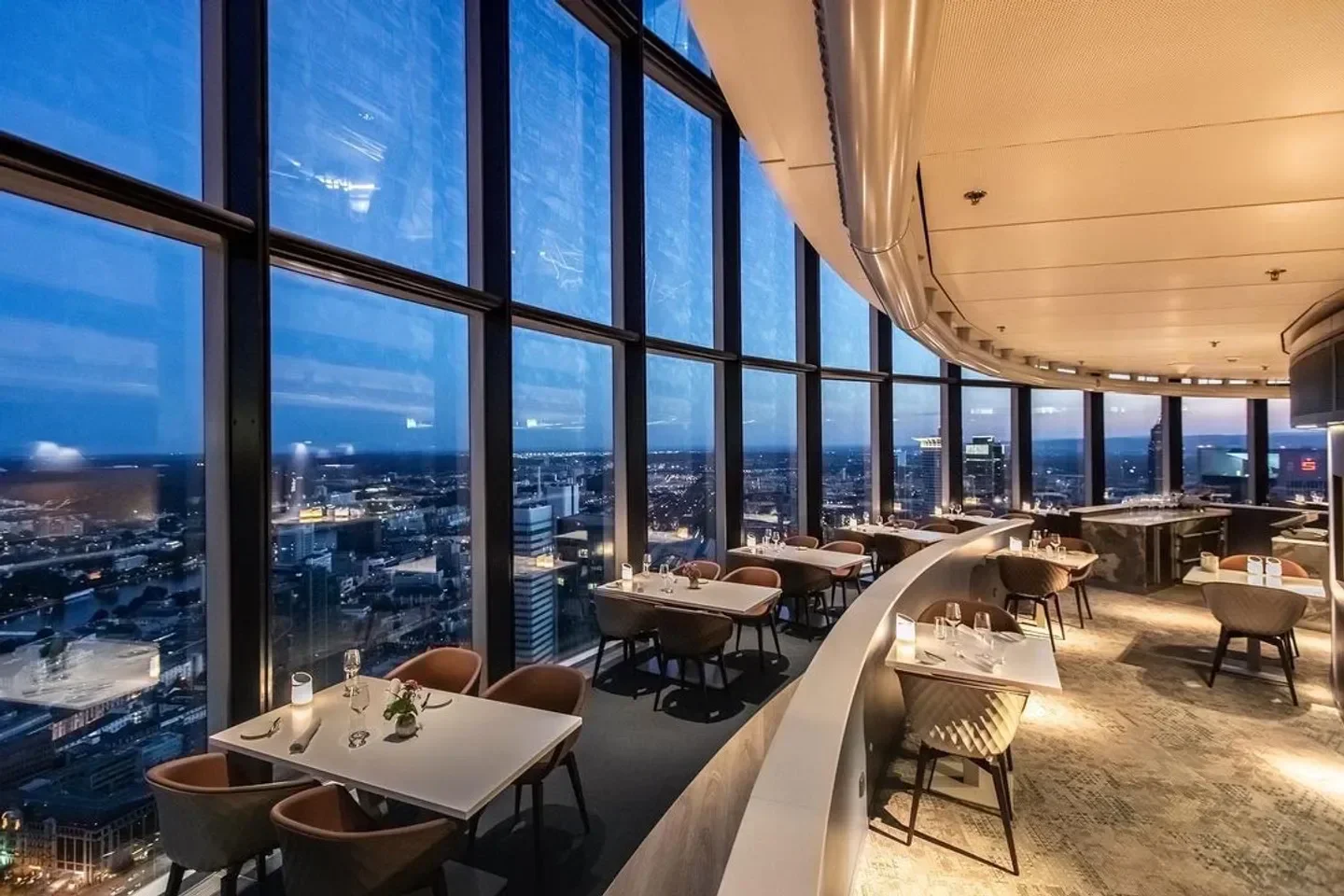 Main Tower Restaurant & Lounge in Frankfurt, elegant dining with city skyline views at dusk.