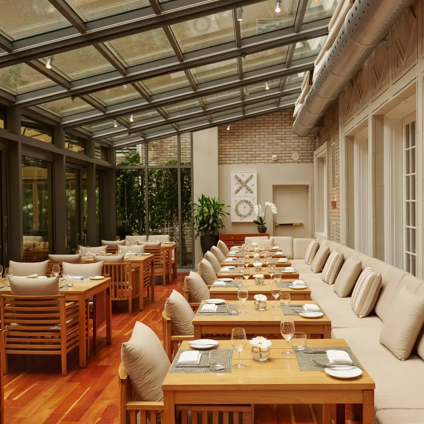 Elegant interior of Maison Boulud in Montreal, featuring wooden tables and a glass ceiling.