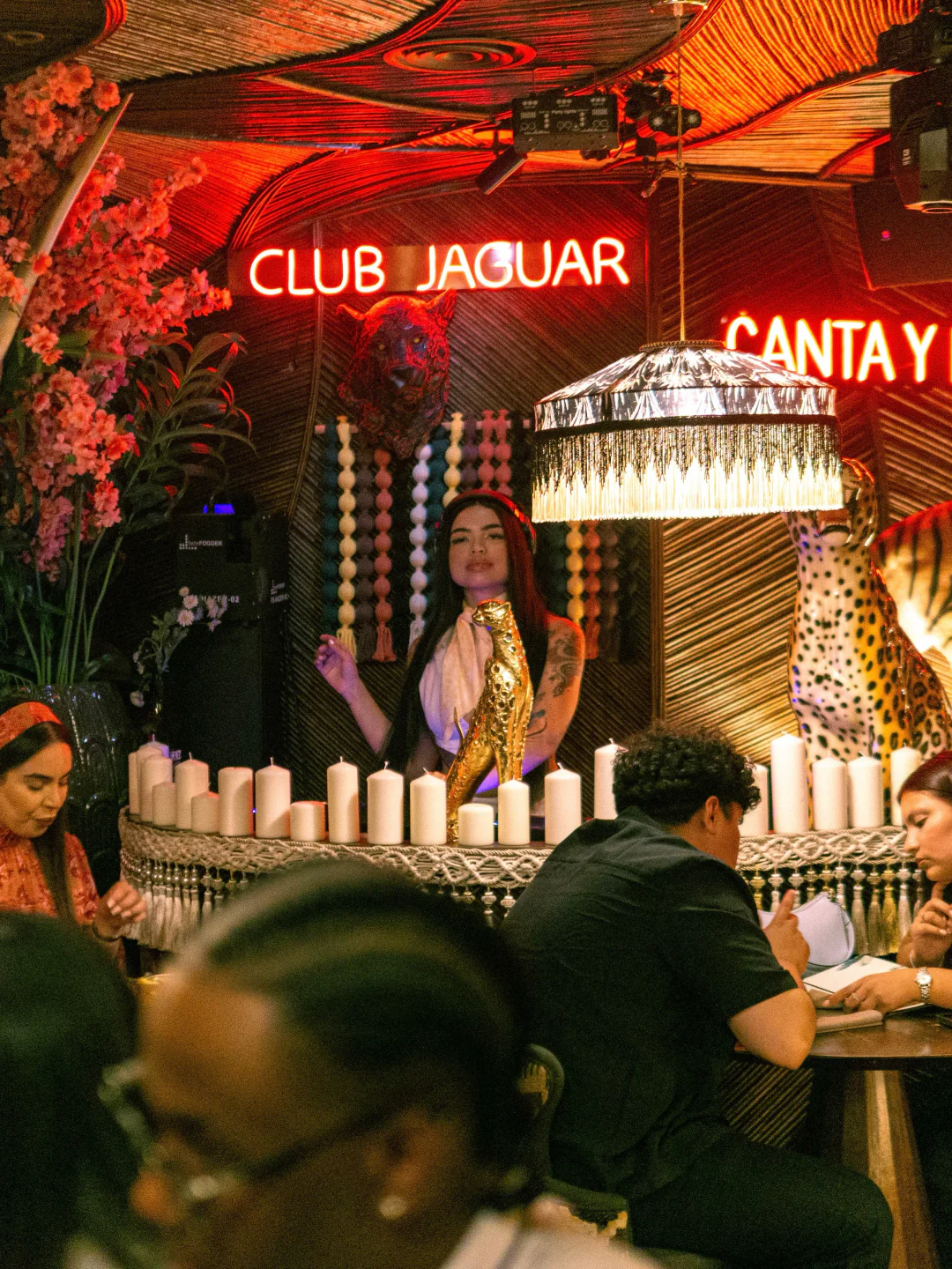 Maison Jaguar restaurant ambiance with neon signs, floral decor, and leopard print accents in the city.
