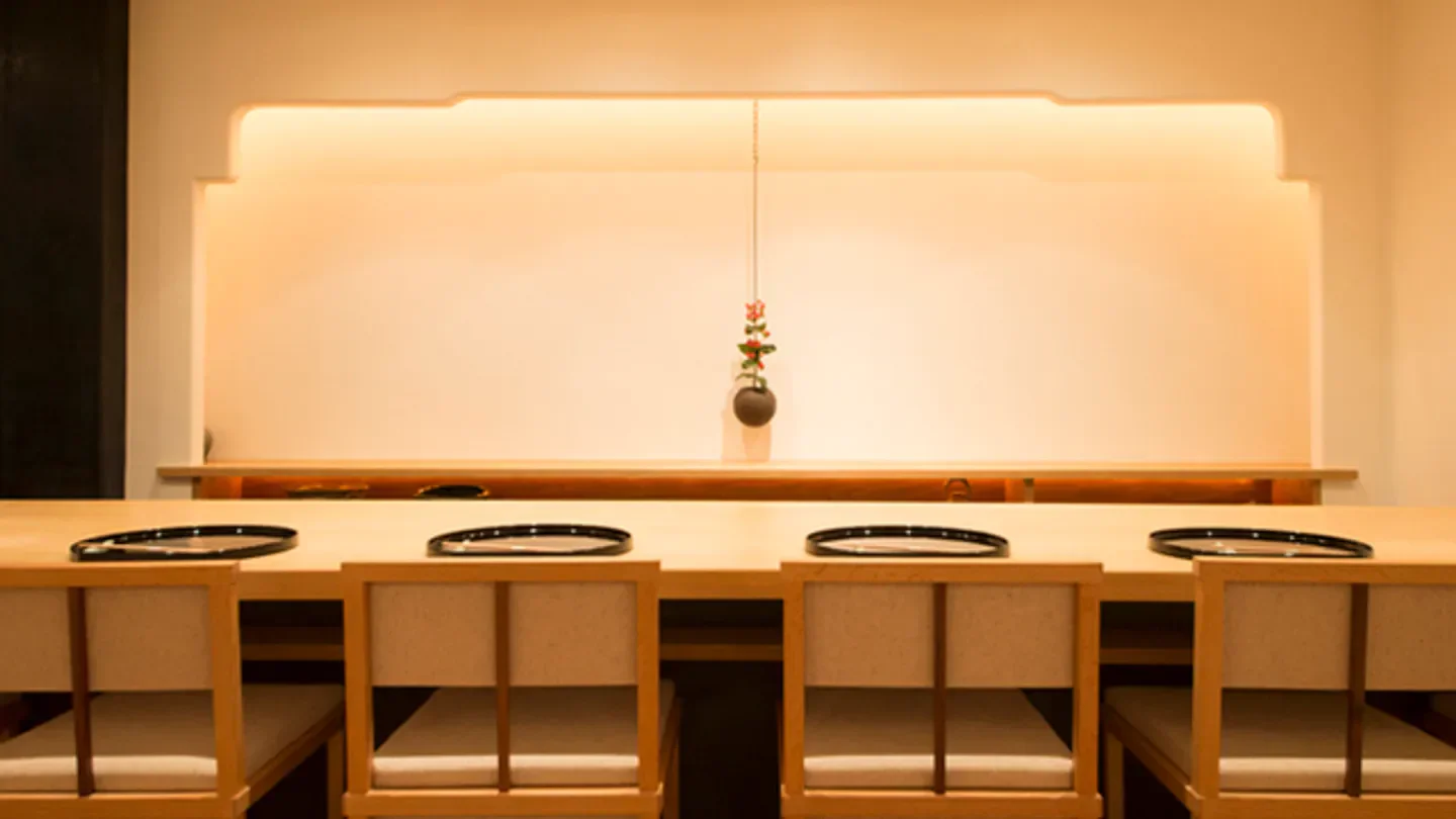 Minimalist interior of Makimura restaurant in Tokyo, featuring wooden tables and elegant decor.