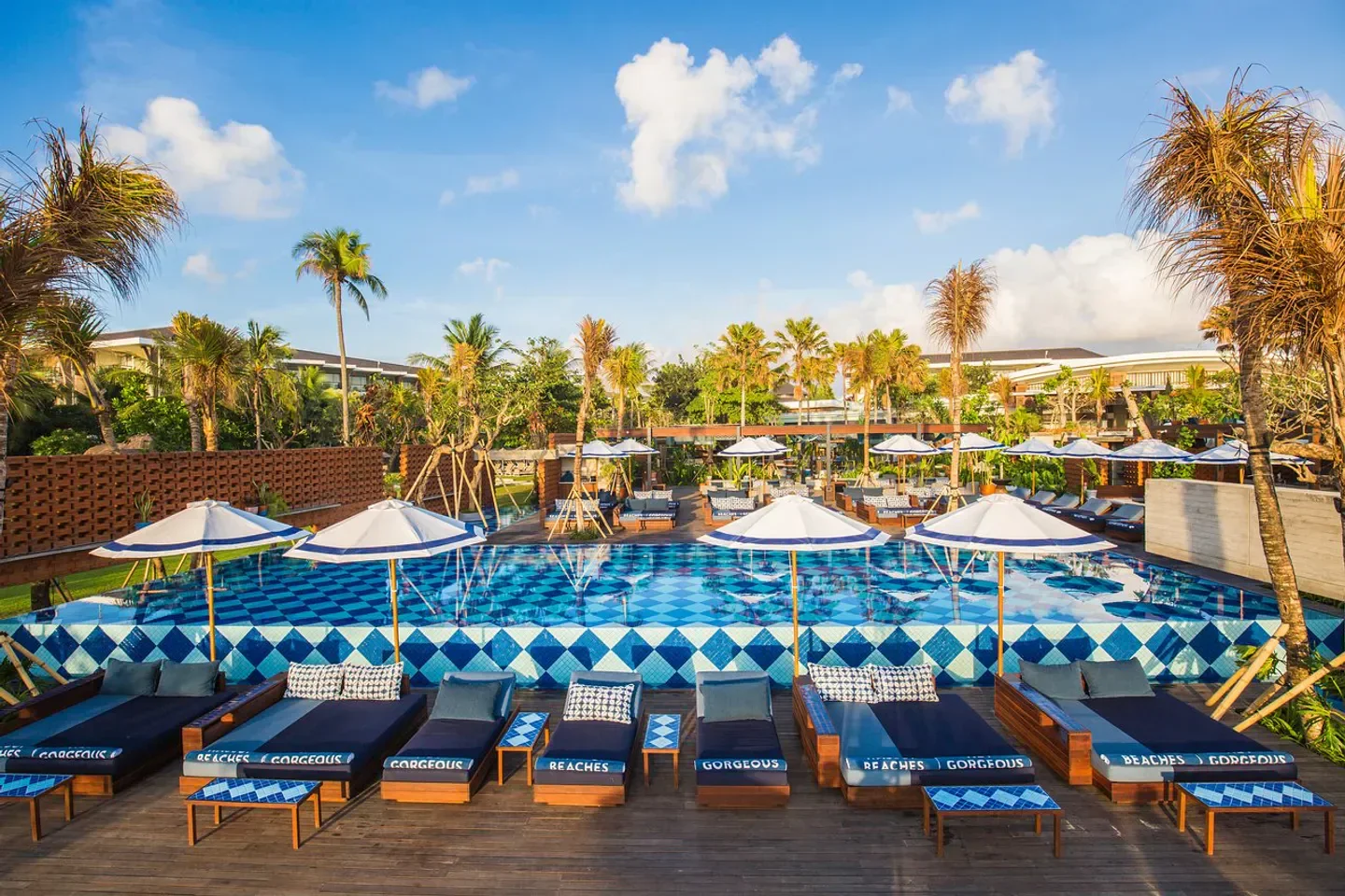Manari Beach House in Bali: Luxurious pool with lounge chairs and umbrellas under a bright sky
