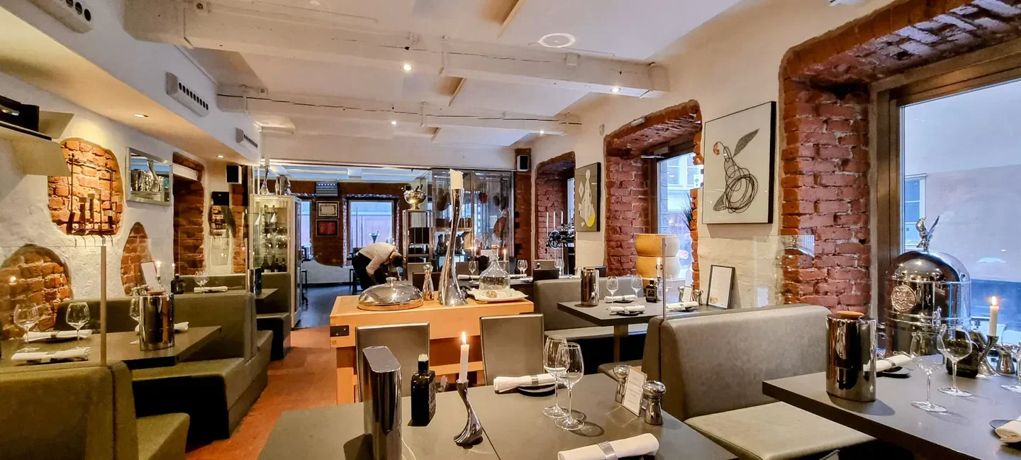 Cozy dining area at Mancini Stockholm restaurant, featuring brick walls and elegant tables.