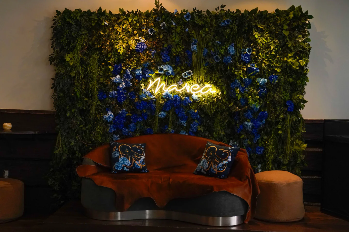 Marea Beverly Hills restaurant features a velvet sofa and a floral wall with neon "Marea" sign.
