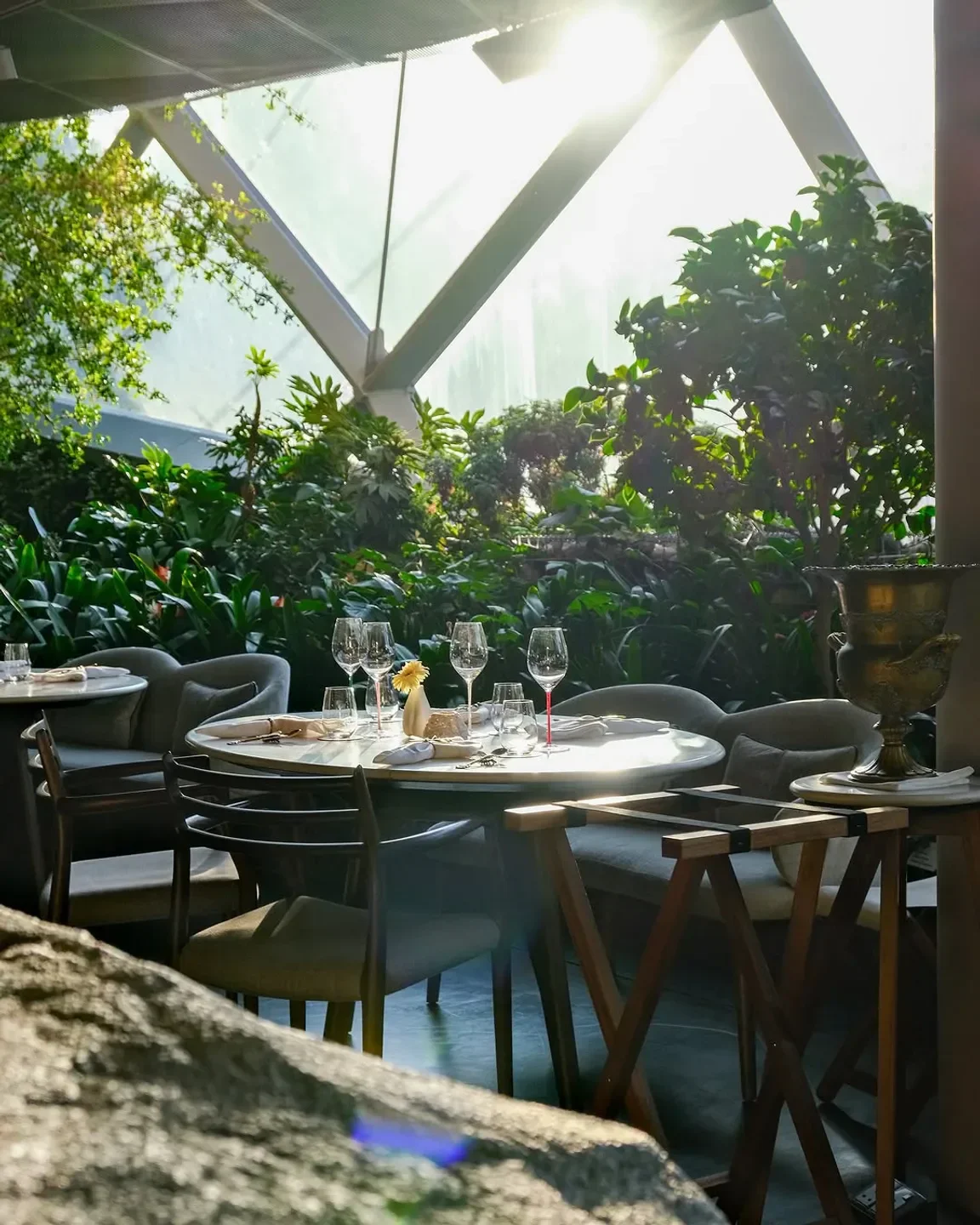 Dining space at Marguerite restaurant in Singapore, surrounded by lush greenery and sunlight.