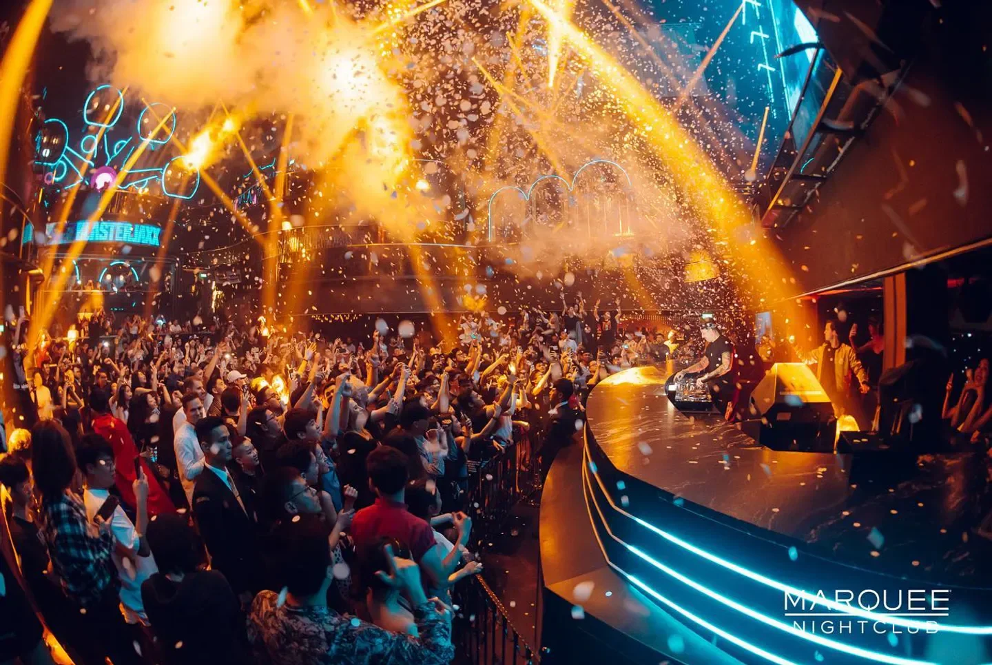 Energetic crowd at Marquee nightclub in Singapore, confetti and lights illuminate the scene.