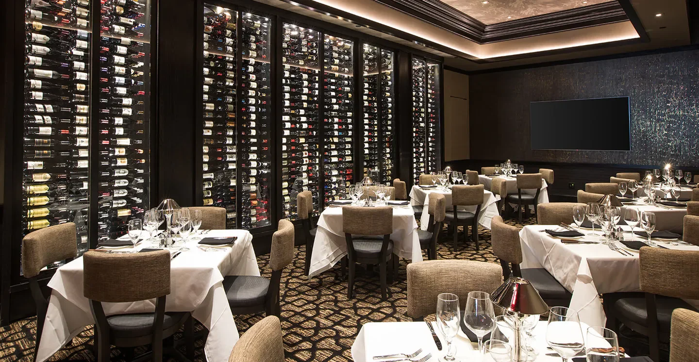 Elegant dining room at Mastro's Steakhouse - Houston with wine display and tables.