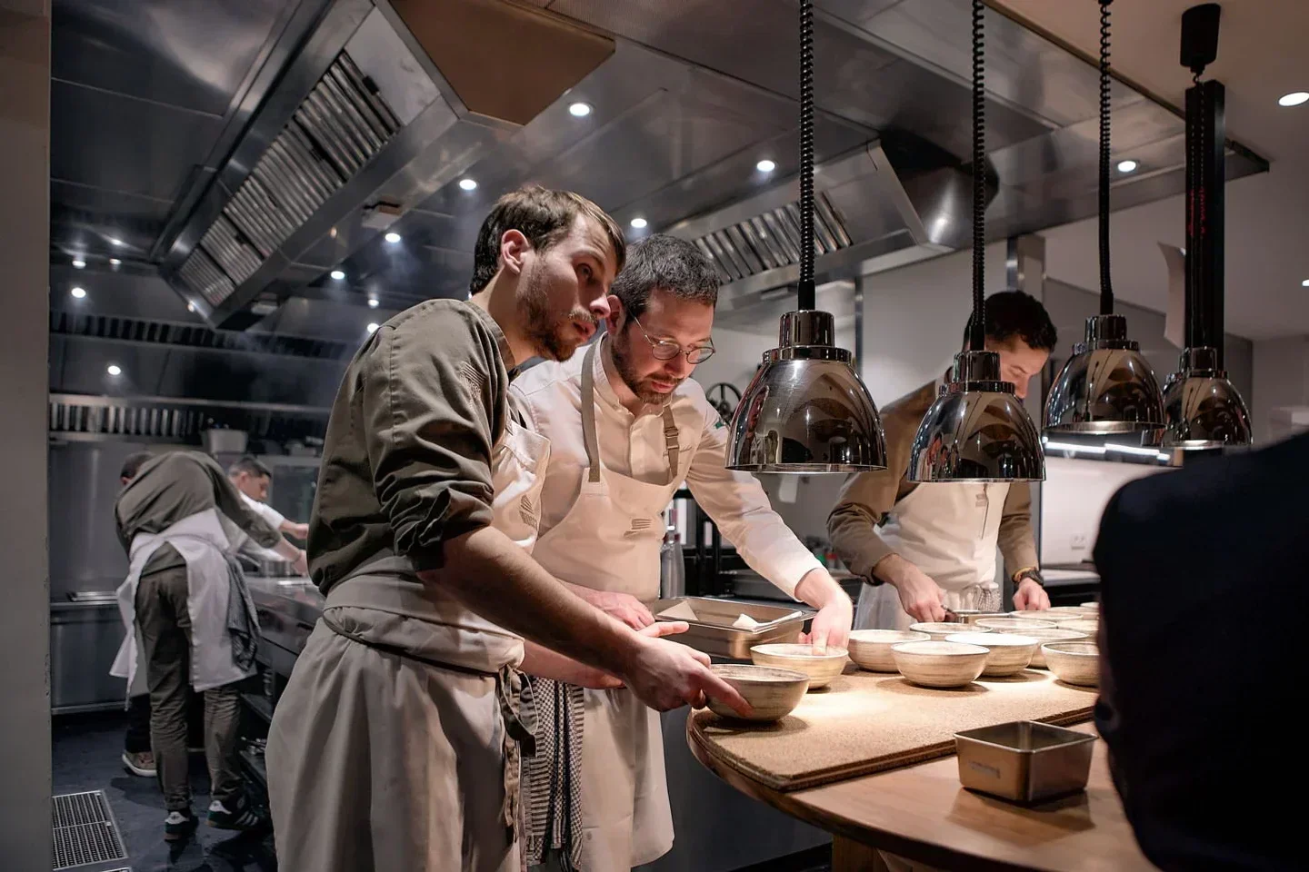 Chefs at work in the kitchen of Menssa restaurant in Brussels, preparing dishes.