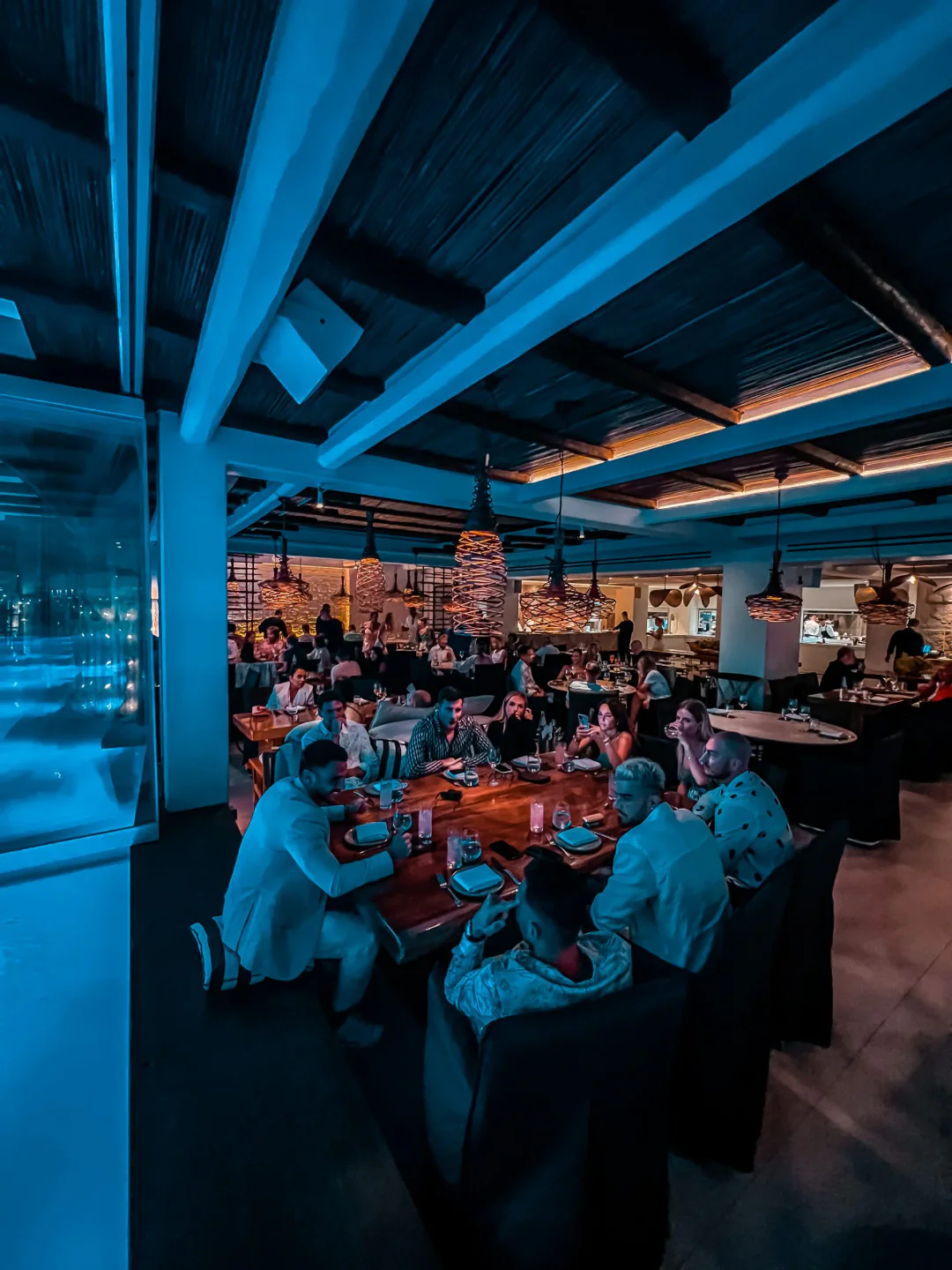 Meraki restaurant in Mykonos with its stylish interior, featuring guests dining under unique pendant lights.