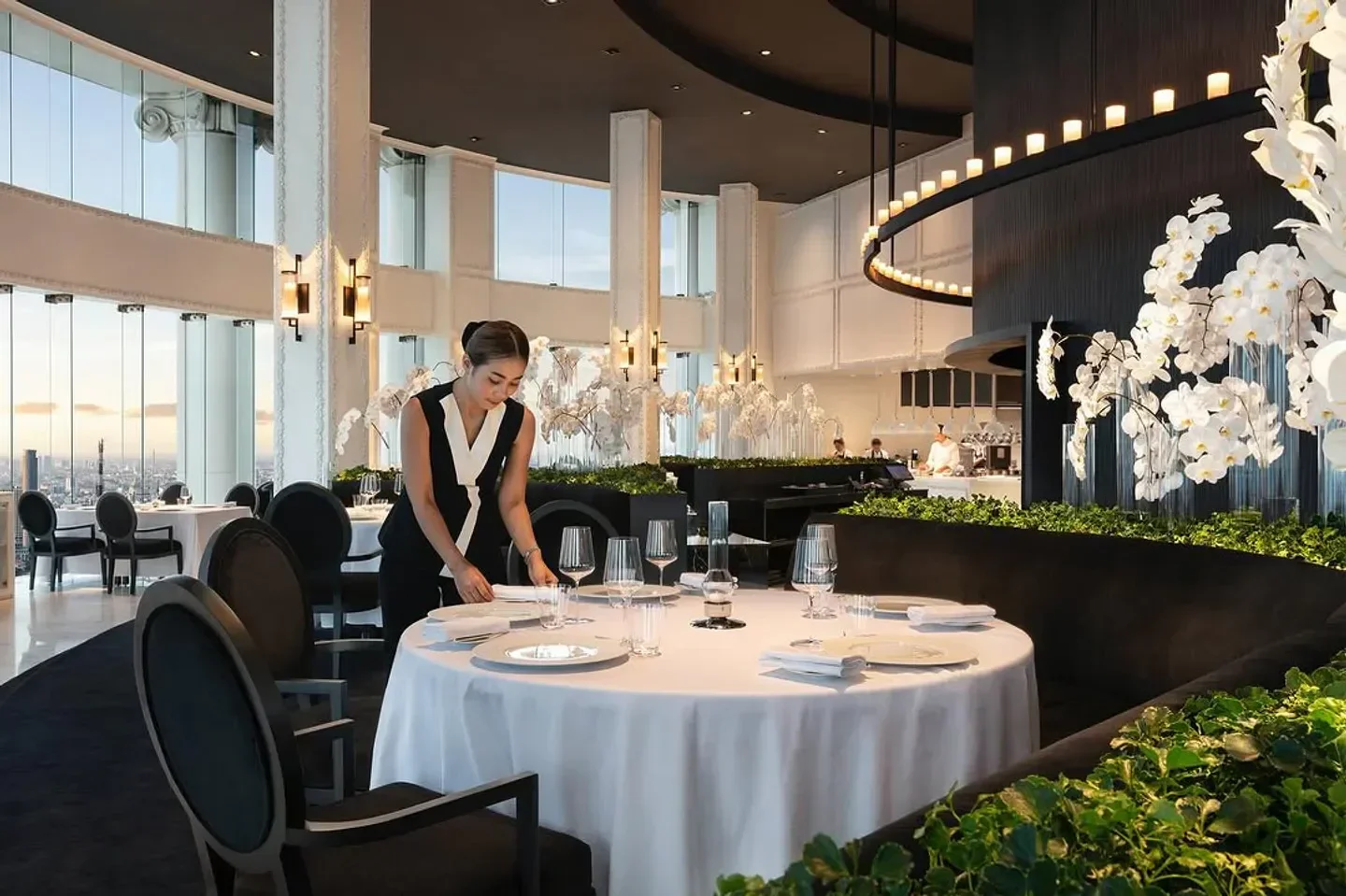 Elegant dining at Mezzaluna Bangkok, setting a table with city views and floral accents.