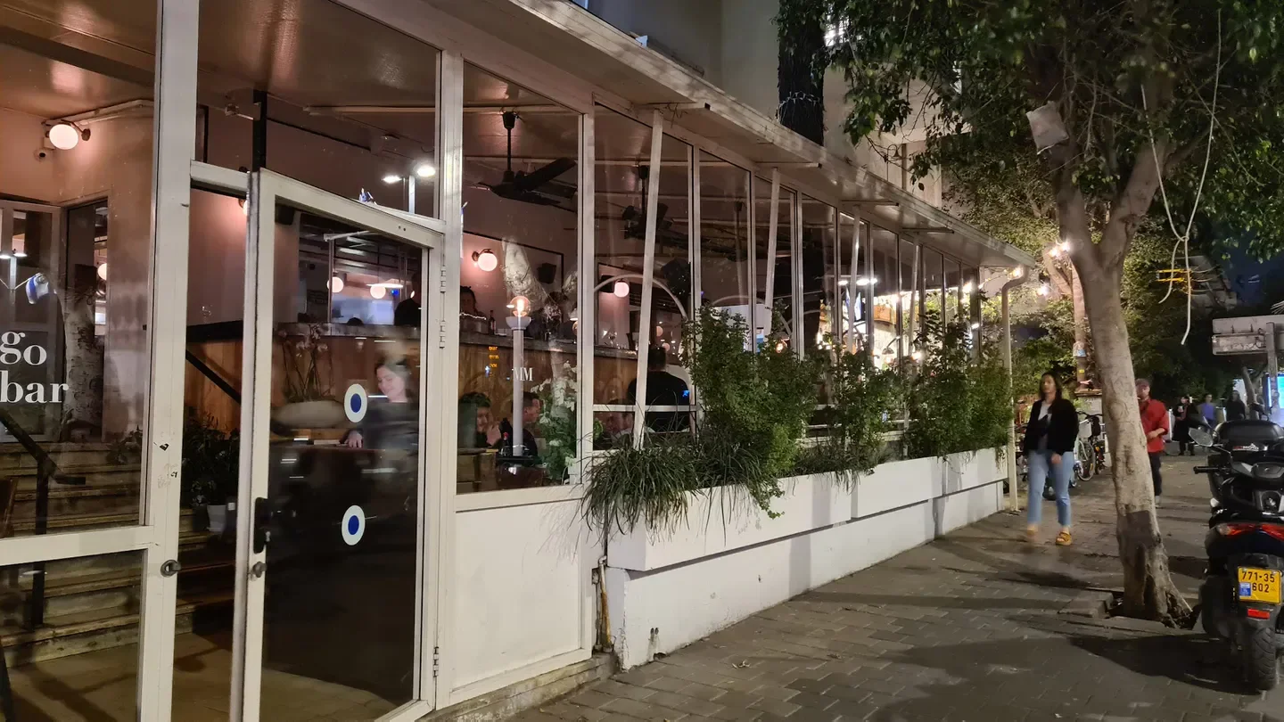 Exterior of Milgo & Milbar restaurant in Tel Aviv at night with people visible