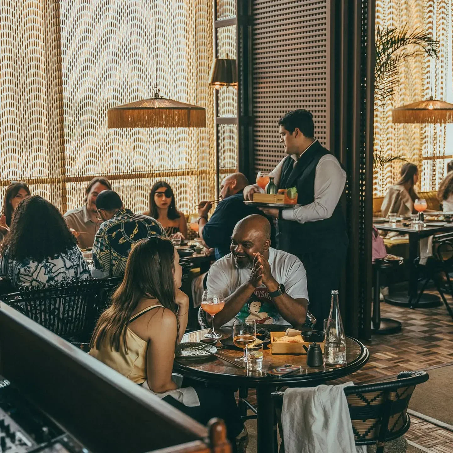 Dining at Mimi Kakushi Dubai: elegant interior and a waiter serving cocktails.
