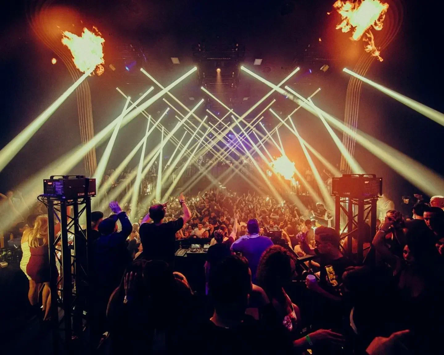 Energetic crowd at Mirano Continental nightclub in Brussels with dramatic lighting and flames.