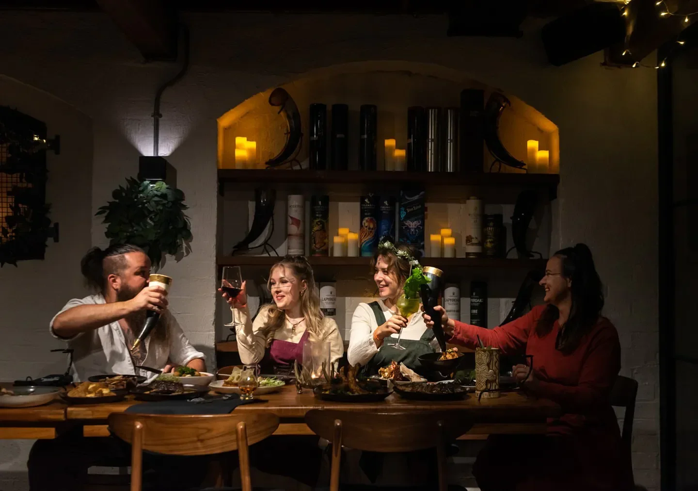 Group cheers at Mjølner restaurant in Sydney. Dark, cozy interior with food and drinks.