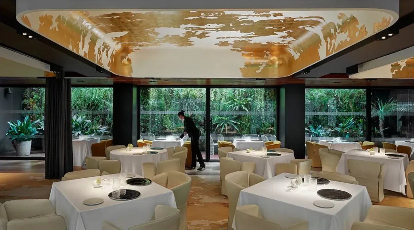 Elegant dining room at Moments restaurant in Barcelona, with nature views and artistic ceiling.