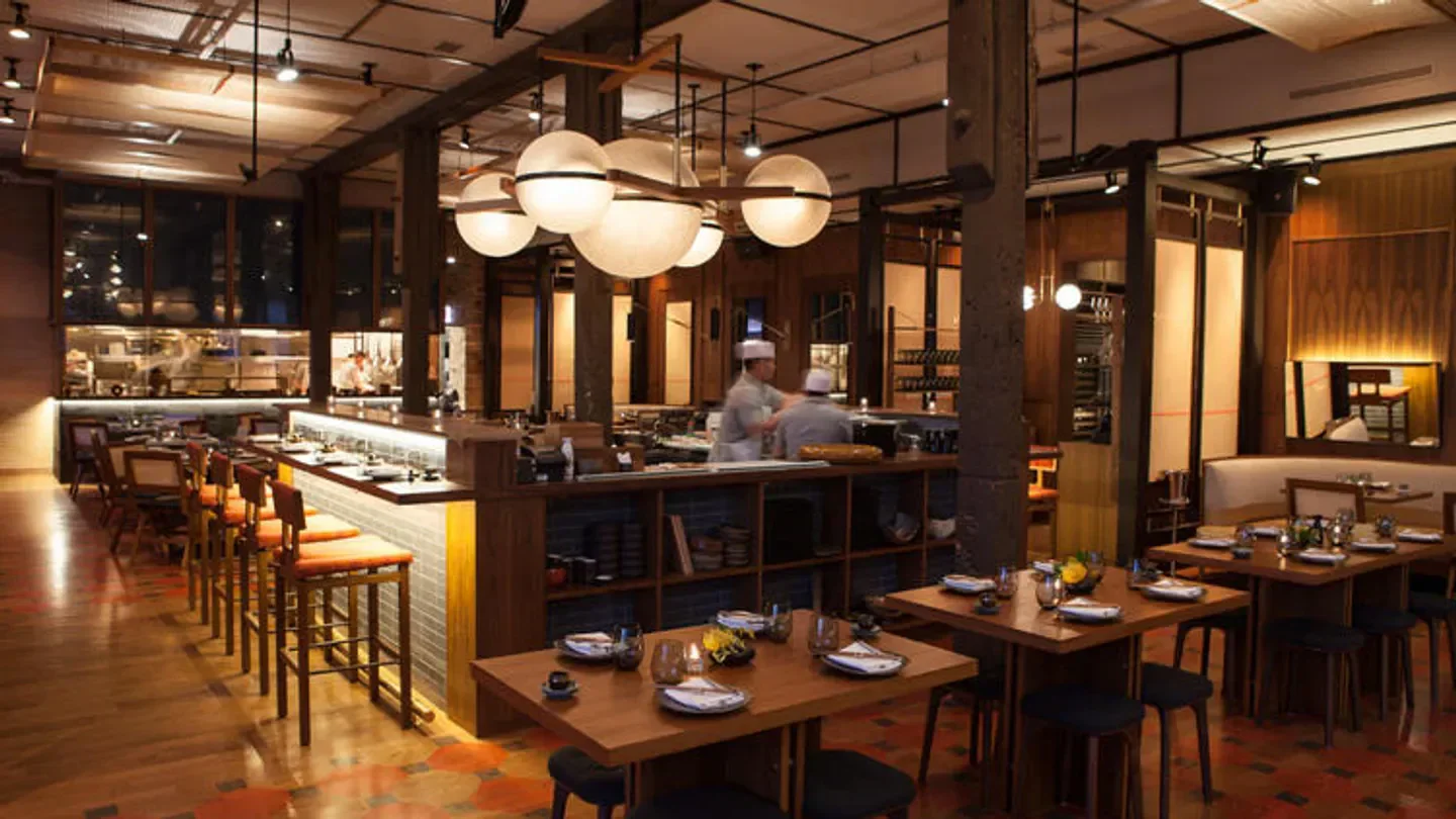 Interior of Momotaro restaurant in Chicago, with tables, bar seating, and kitchen.