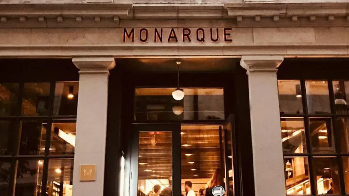 Entrance of Monarque restaurant in Montreal, with inviting warm lighting and open door.