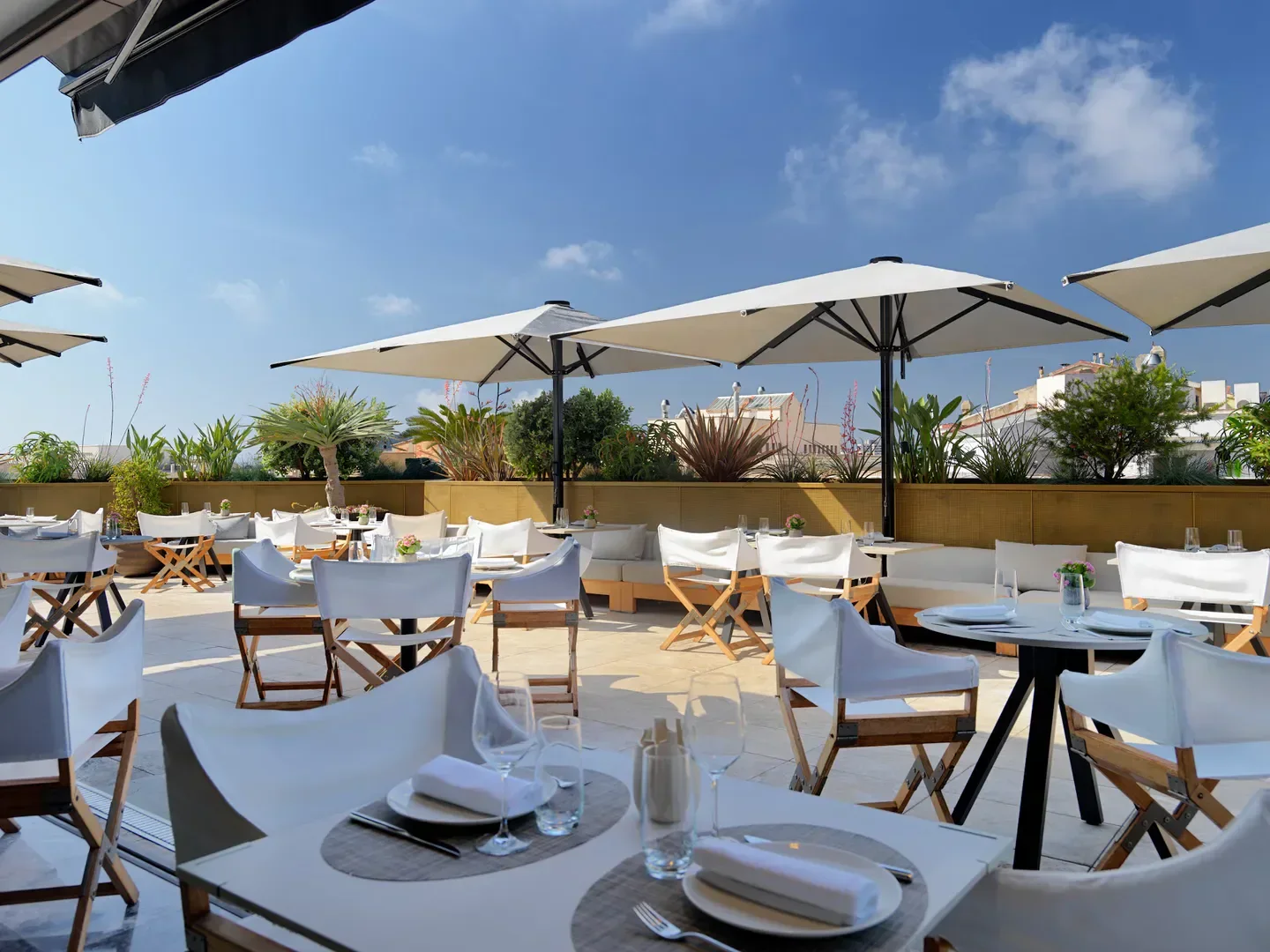 Outdoor dining at Mood Rooftop in Barcelona with white furniture and umbrellas.