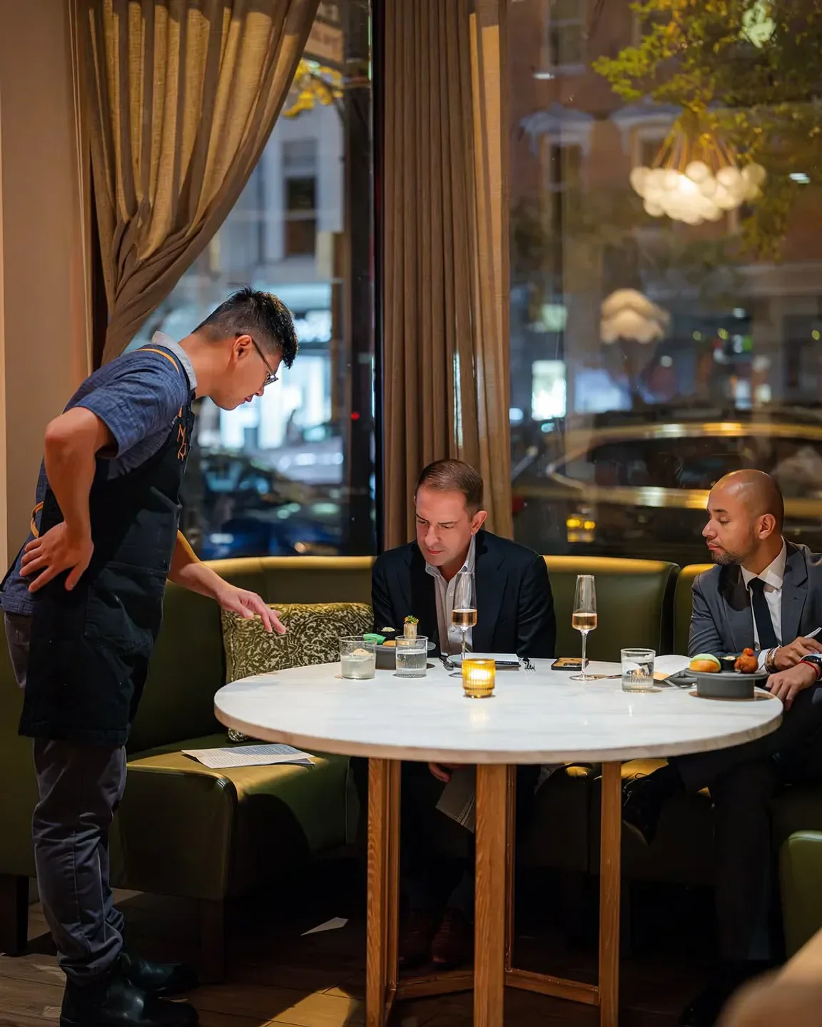 Server at Moon Rabbit in Washington, DC, explains dish to guests at a table.
