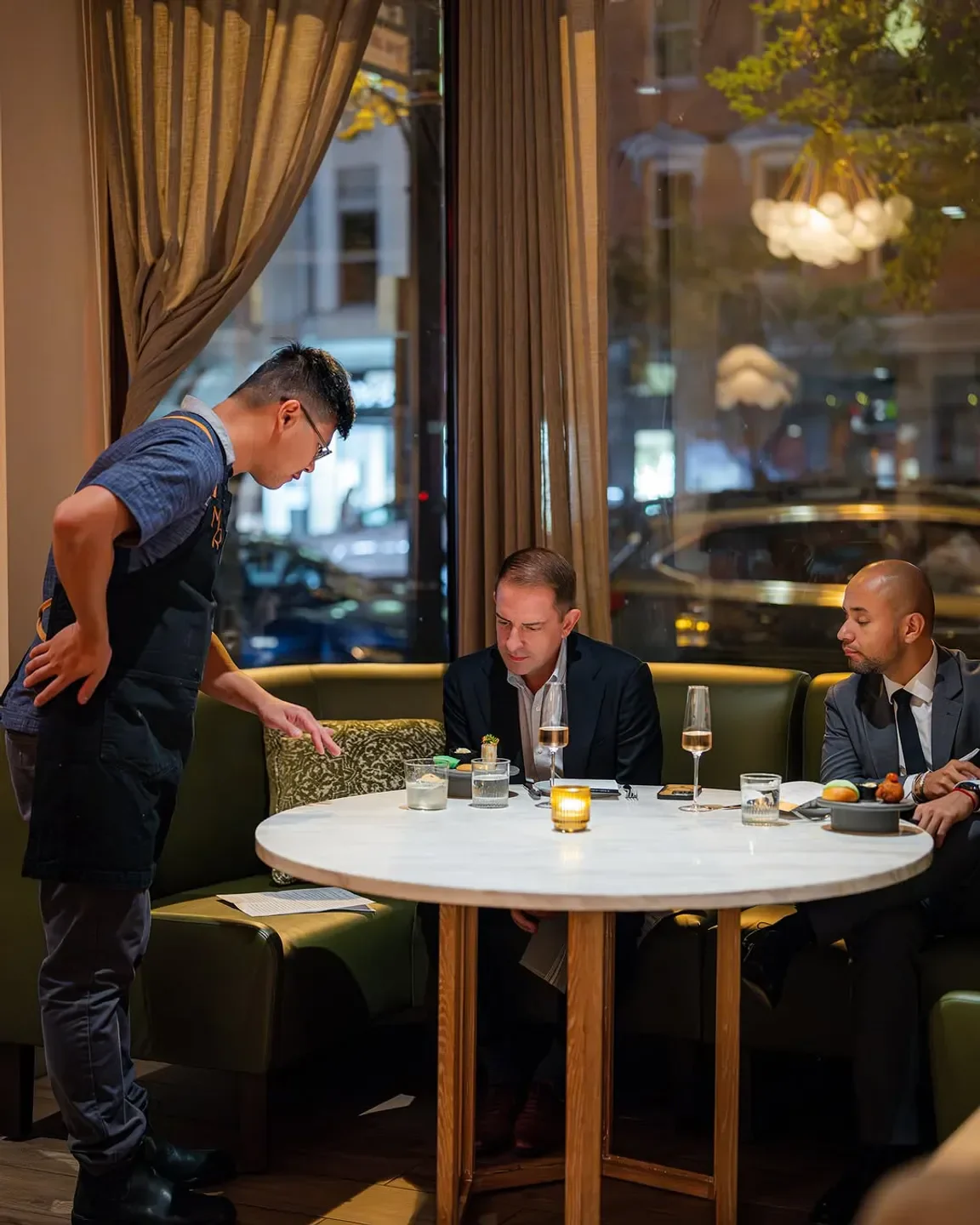 Server at Moon Rabbit in Washington, DC, explains dish to guests at a table.