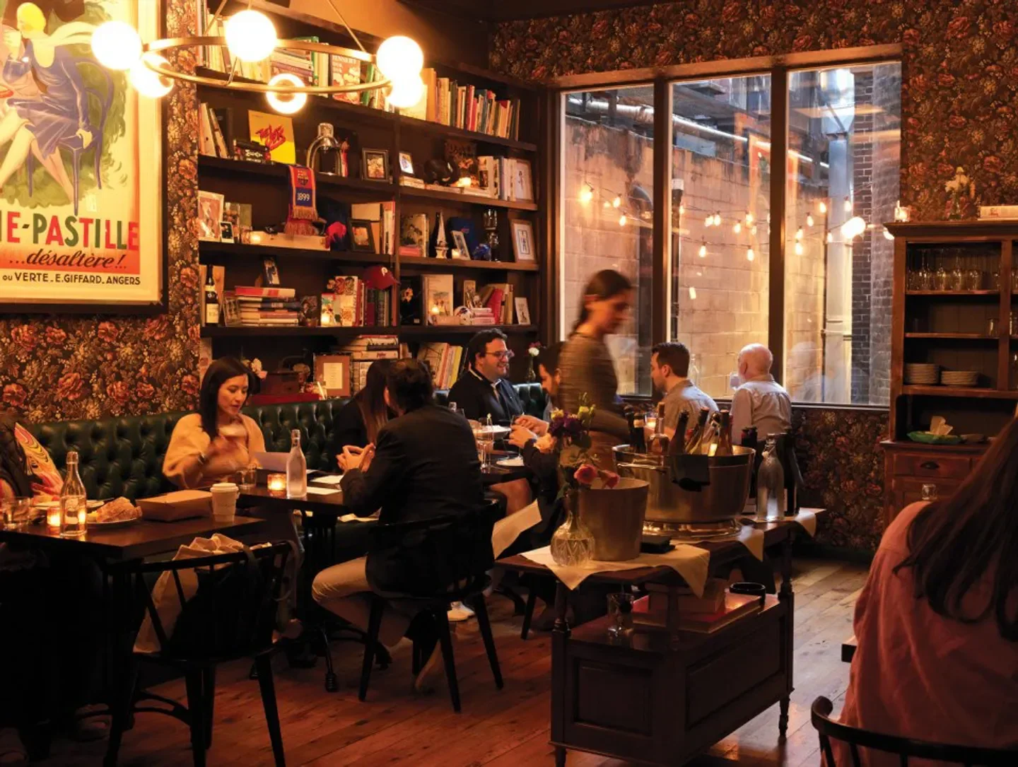 Cozy dining area at My Loup restaurant in Philadelphia, with warm lighting and floral wallpaper.