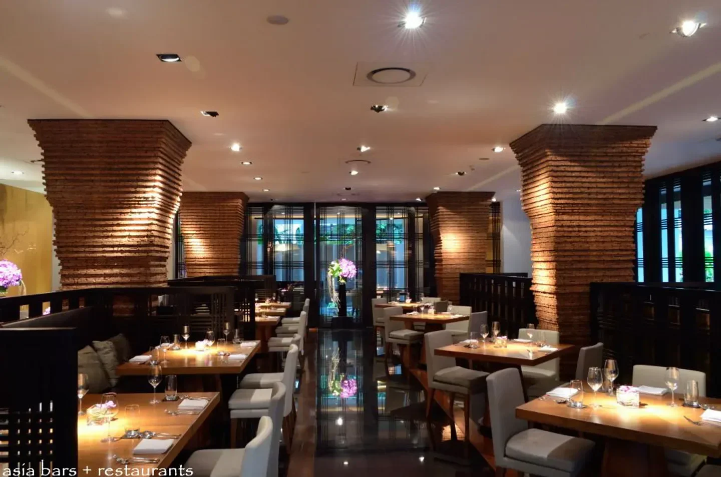 Elegant dining area at Nahm restaurant in Bangkok, featuring brick pillars and tables.