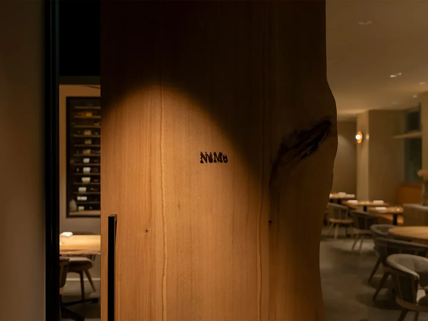 Elegant entrance to NéMo restaurant in Tokyo, showcasing a wooden feature.