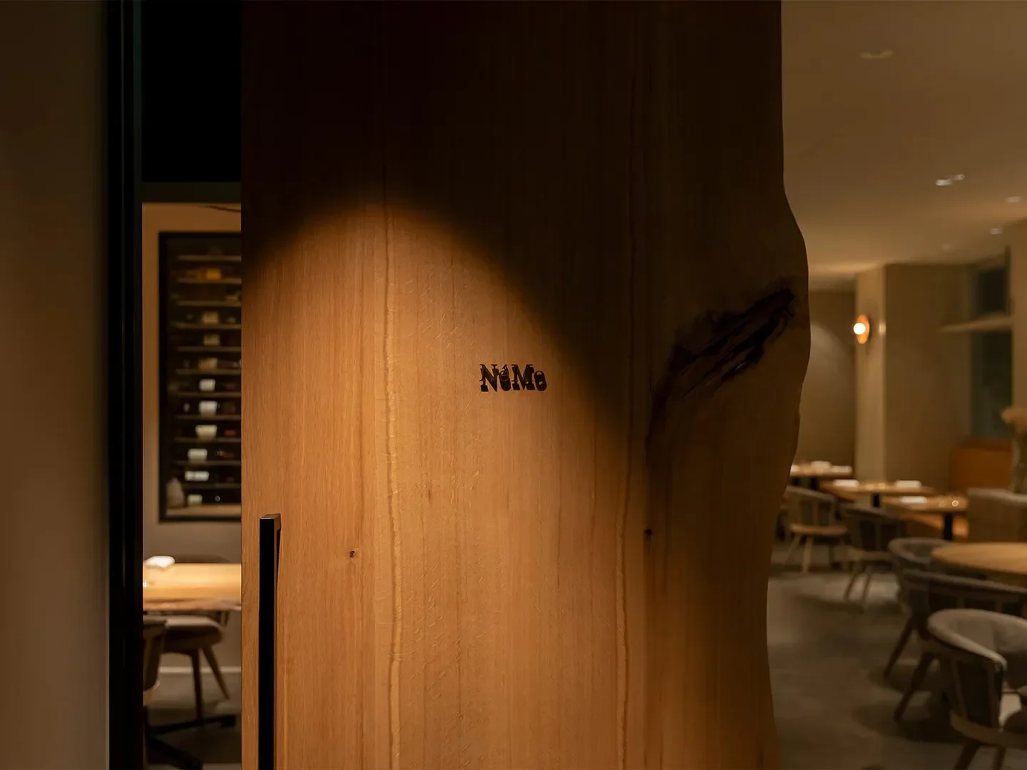 Elegant entrance to NéMo restaurant in Tokyo, showcasing a wooden feature.