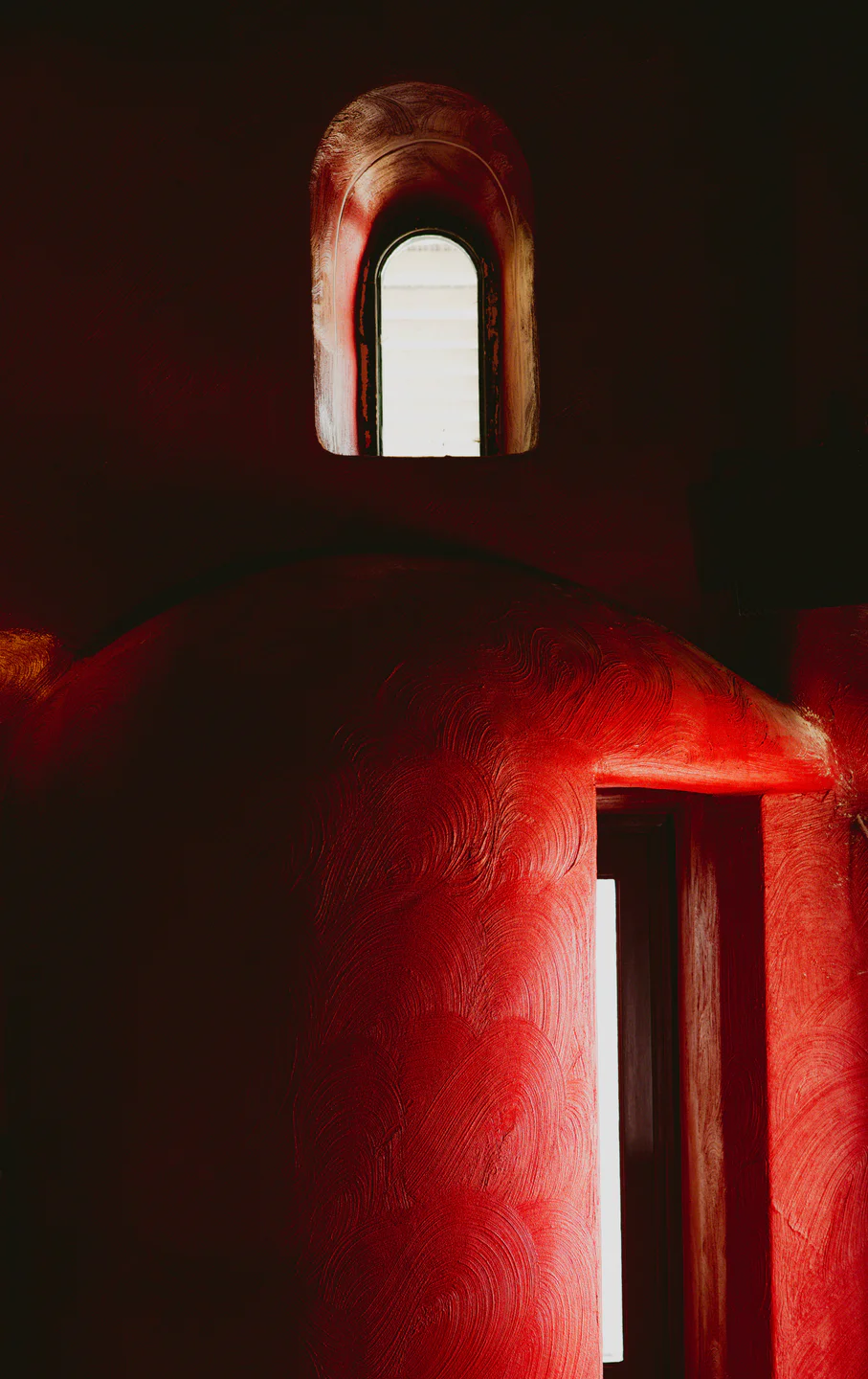Red-lit interior detail at Sapphõ Mykonos with arched window and textured walls