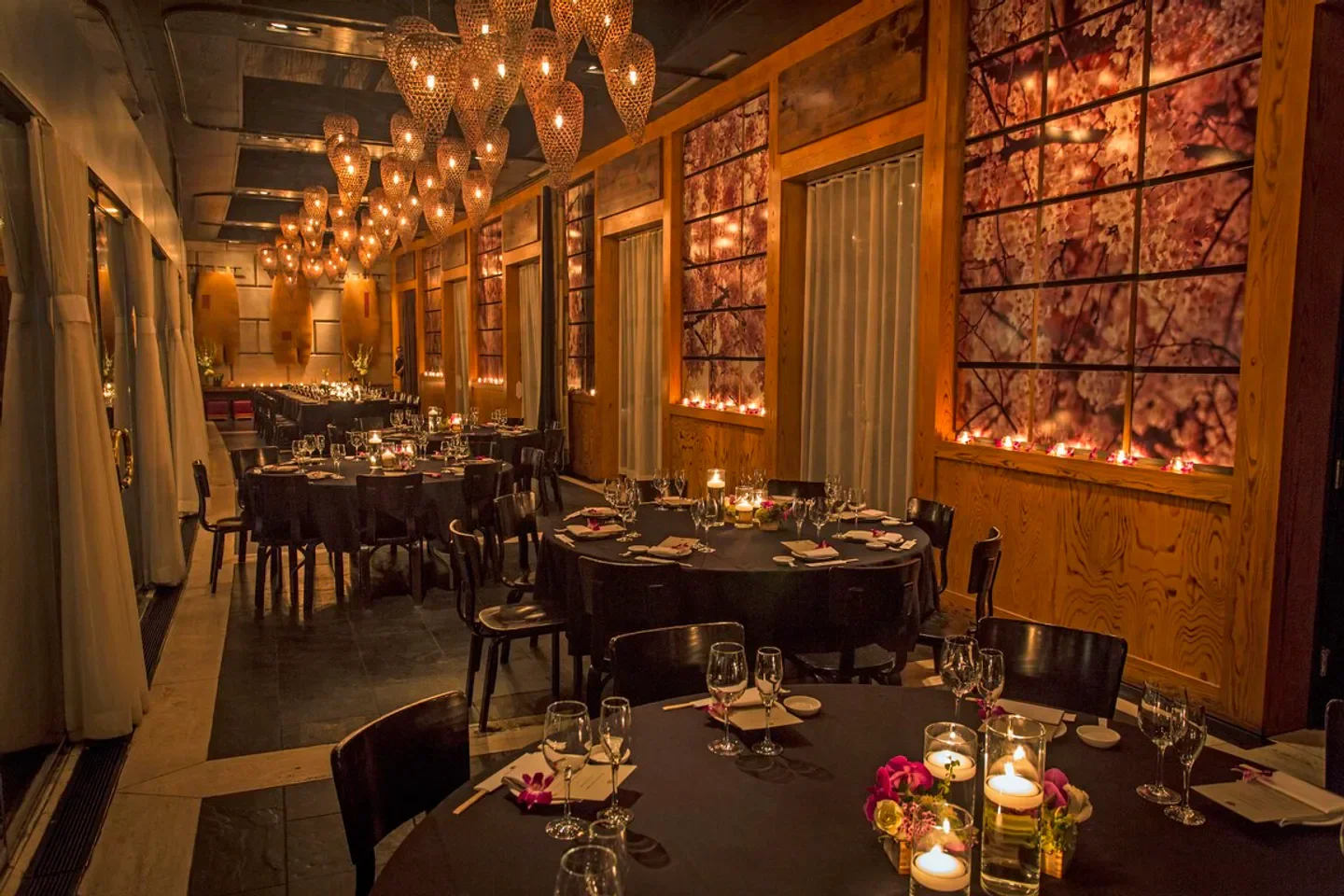 Elegant dining room at Nobu Dallas with round tables set for dinner service.