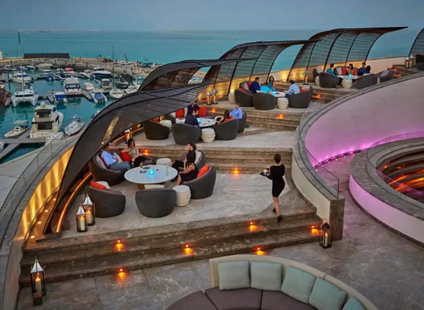 Nobu Doha restaurant's stylish outdoor terrace with harbor views, enjoying a pleasant evening.