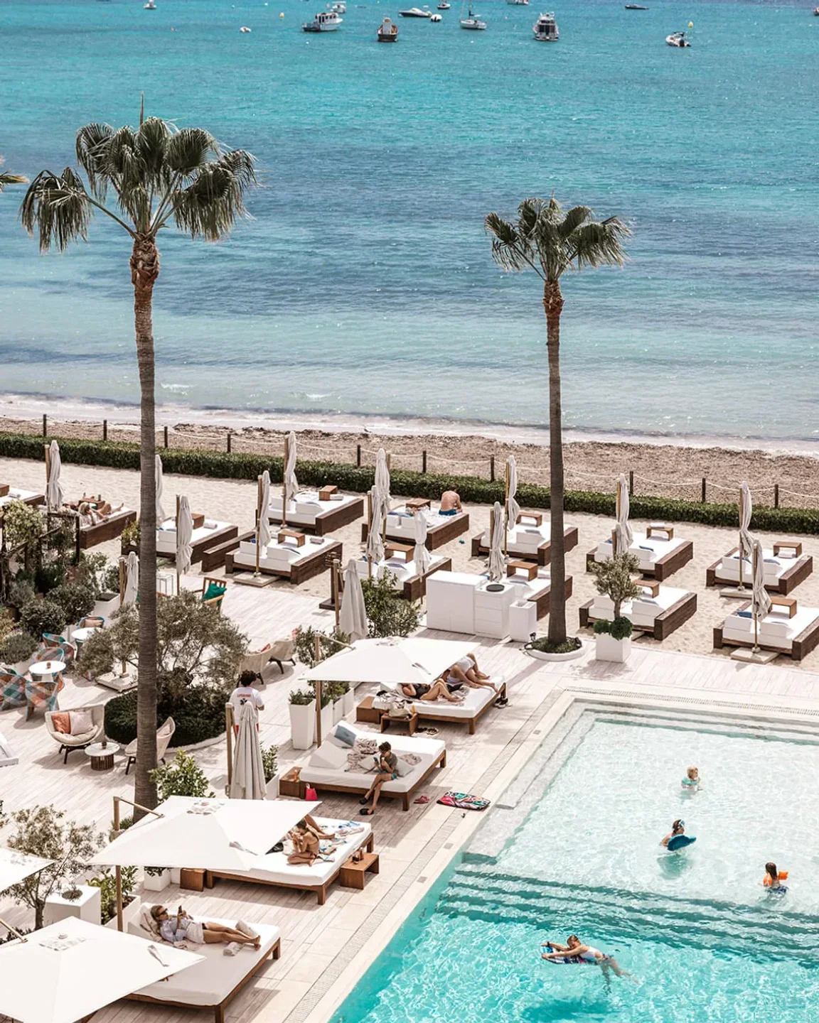 Luxurious pool and beach loungers at Nobu Ibiza Bay, overlooking turquoise waters in Ibiza.