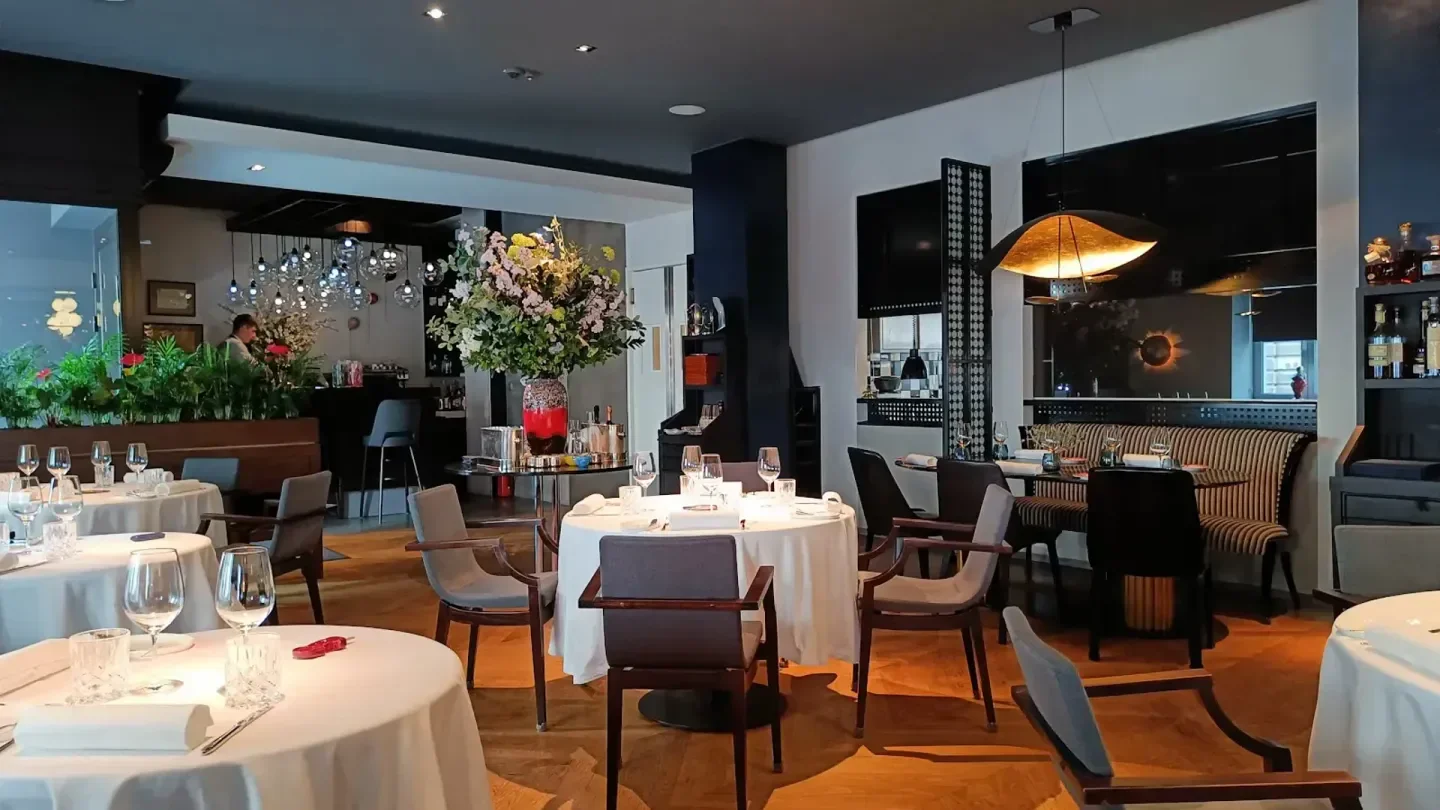 Elegant interior of Nolita restaurant in Warsaw, featuring tables, chairs, and floral arrangements.