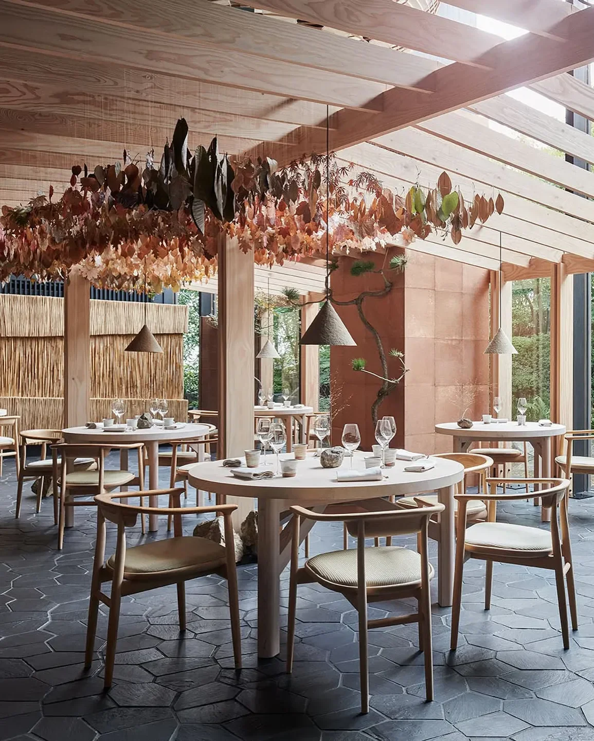 Dining room at Noma in Copenhagen featuring wooden tables and elegant leaf decor
