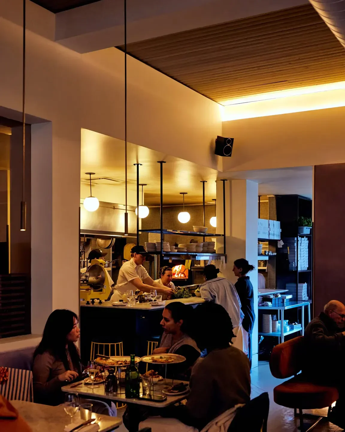 Inside Nora Gray restaurant in Montreal, with chefs, diners, and a warm, inviting atmosphere.
