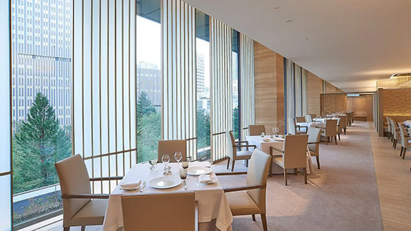 Interior dining space at Nouvelle Epoque in Tokyo with city views through tall windows.