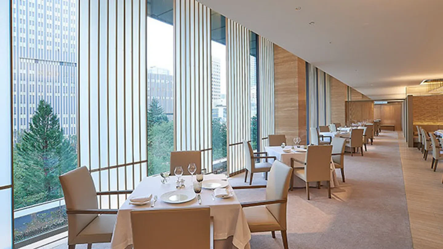 Interior dining space at Nouvelle Epoque in Tokyo with city views through tall windows.